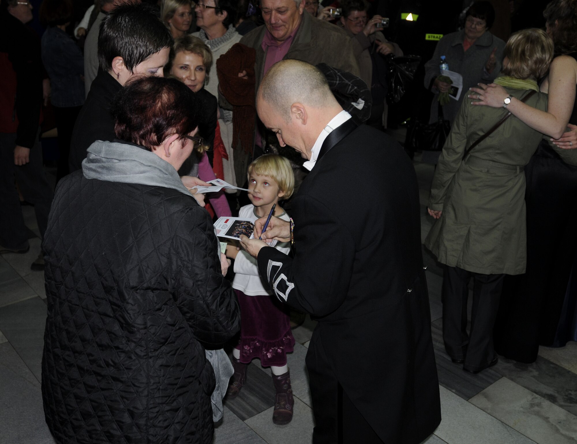 RADLIN, Poland – Maj. Matt Henry, U.S. Air Forces in Europe Band commander and musical director, signs a program for some concert attendees here at the Radlin City Center of Sports and Recreation Oct. 23 following the band’s concert.  The USAFE Band is performing six concerts in six days, Oct. 20-25, in support of USAFE's international relations program in partnership with the U.S. State Department.  Four hundred people from Radlin attended this concert which commemorates 90 years of diplomatic relations between the United States and Poland.  (U.S. Air Force photo/Master Sgt. Kelley J. Stewart)