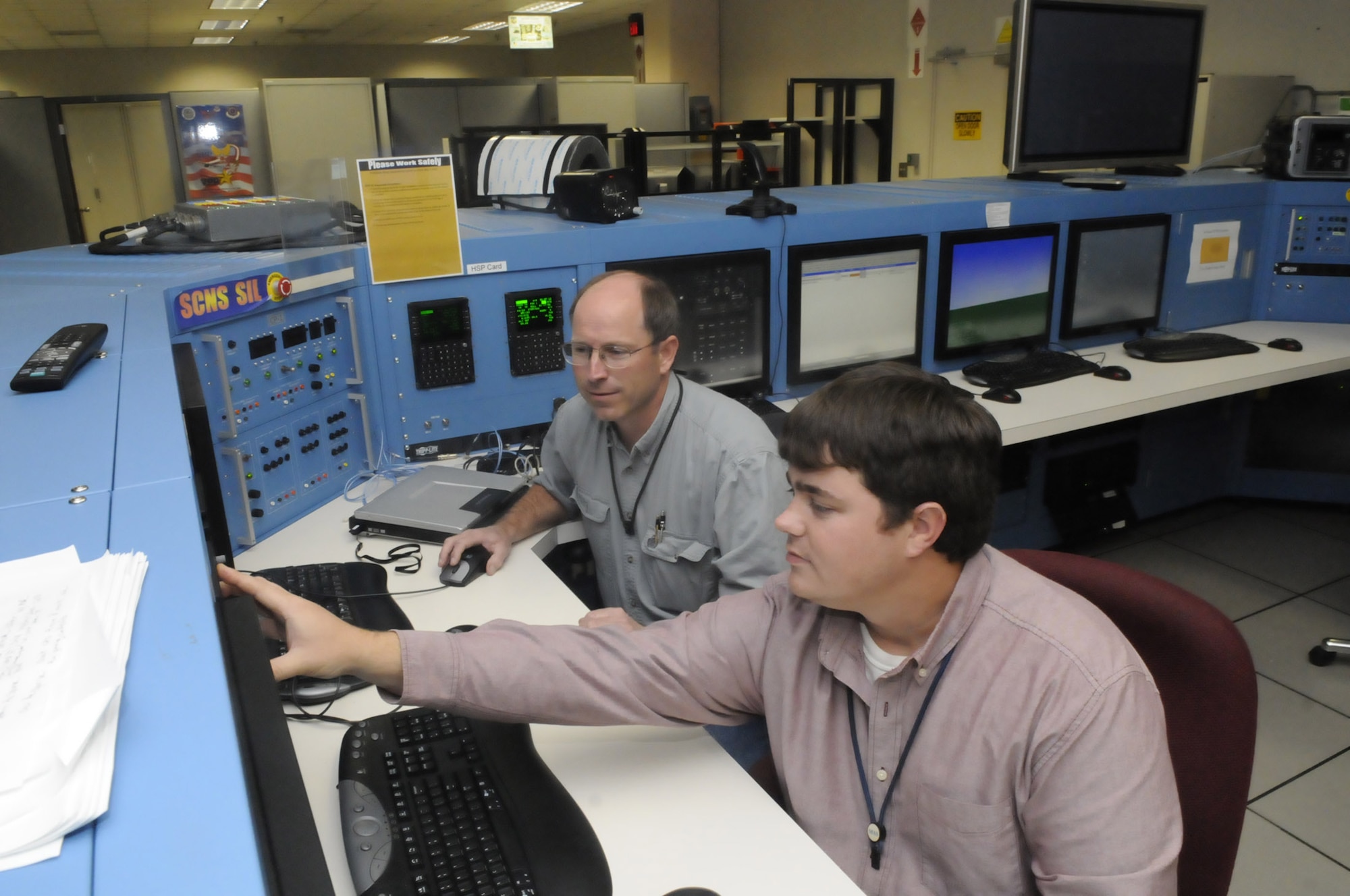 L-R Rusty Drummond and Jason Crawford work at the self contained navigation system console. The system is used on many C-130s. U. S. Air Force photo by Sue Sapp