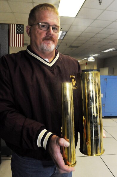Steve Pollard displays shell casings from a 40 mm Bofors cannon and a 105 mm Howitzer cannon, guns used on the C-130 Gunship. U. S. Air Force photo by Sue Sapp