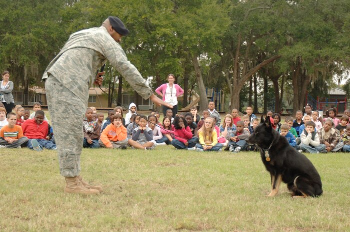 Students and faculty at Hunley Park Elementary watched as Staff Sgt. Ramon Alexander demonstrated how he communicates with his dog Waldo by giving the command down during a drug search demonstration held at the school, Oct. 27. The 437th Security Forces Squadron's military working dog kennels conducted the demonstration as part of Red Ribbon week which raises public awareness and mobilize communities to combat tobacco, alcohol and drug use among military personnel, civilians and thier families. Sergeant Alexander is a dog handler with the 437th Security Forces Squadron. (U.S. Air Force photo/Staff Sgt. Marie Brown)