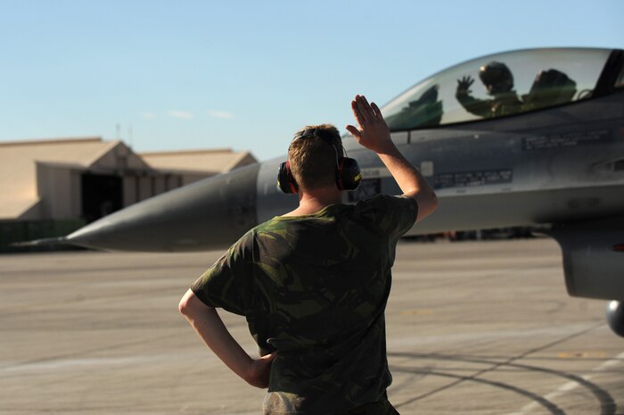 NELLIS AIR FORCE BASE, Nev. -- 1st Sgt. De Heij Huitema a crew chief from the Royal Netherlands Air Force waves good bye and good luck to Capt. Jokob Devenpeck before a training mission at Red Flag 10-1.  Red Flag is a realistic combat training exercise involving the air forces of the United States and its allies. The exercise is conducted on the 15,000-square-mile Nevada Test and Training Range, north of Las Vegas. (U.S. Air Force photo by Tech. Sgt. Michael R. Holzworth)(Released)