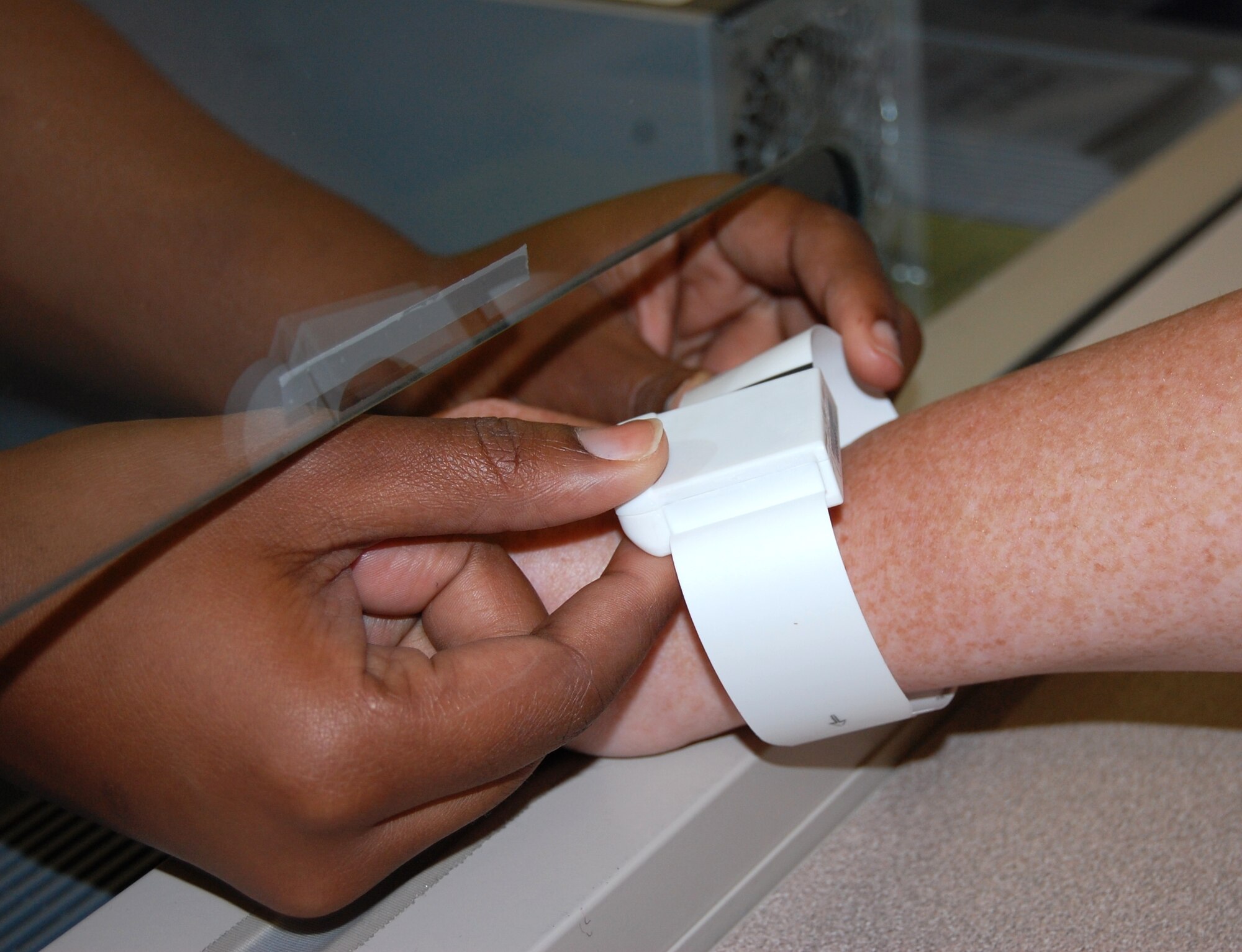 A member of Keesler’s emergency services staff places an RFID device on a patient’s wrist during check in.  (U.S. Air Force photo by Steve Pivnick)