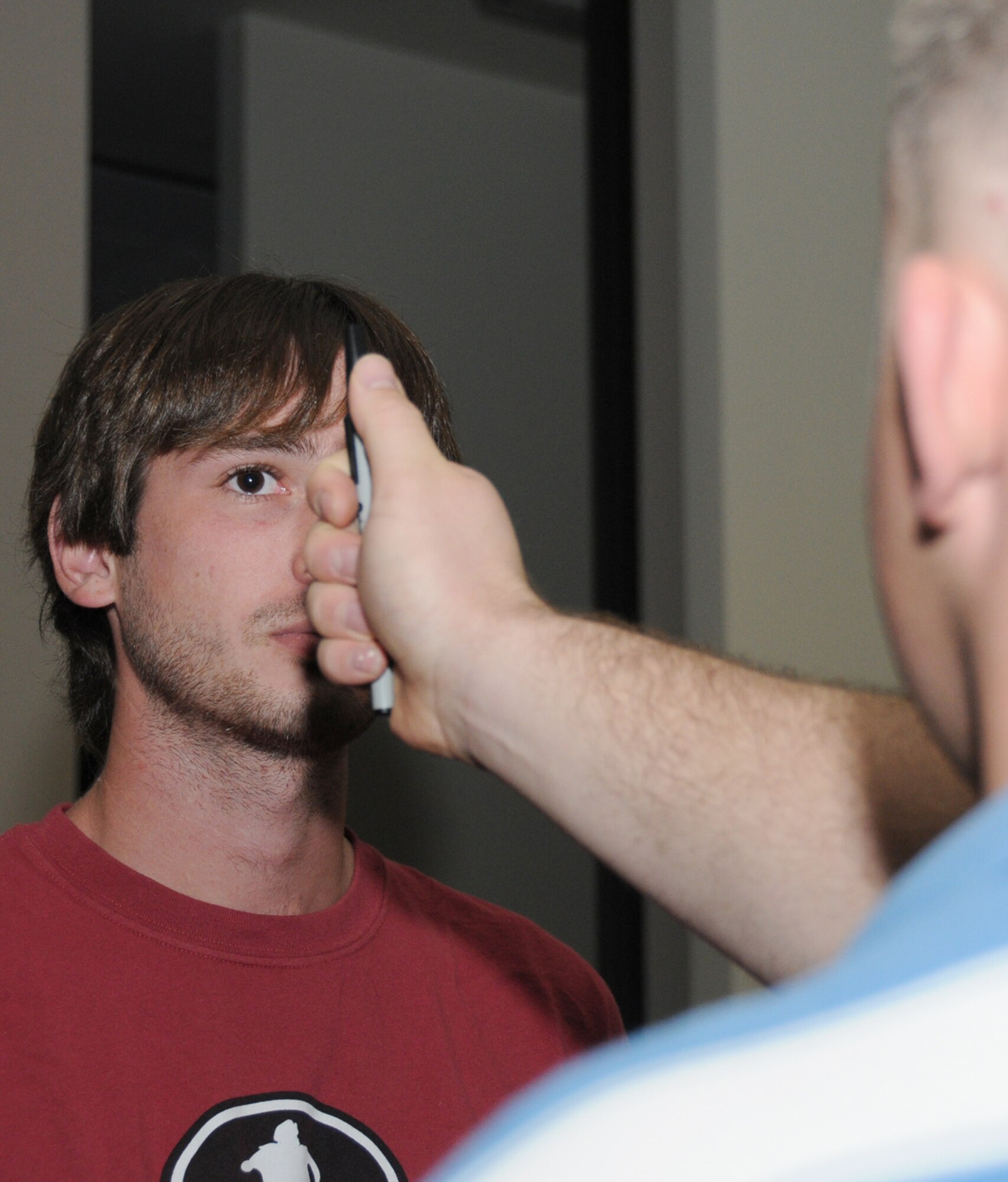 Samuel Foster Jr., left, son of Sam Foster, 81st Training Wing, watches as Senior Airman Ryan Steelman, 81st SFS, conducts a sobriety training test called a horizontal gaze nystagmus.  Foster was one of 10 intoxicated volunteers who gave the law enforcers an opportunity to practice field sobriety tests.  (U.S. Air Force photo by Kemberly Groue)