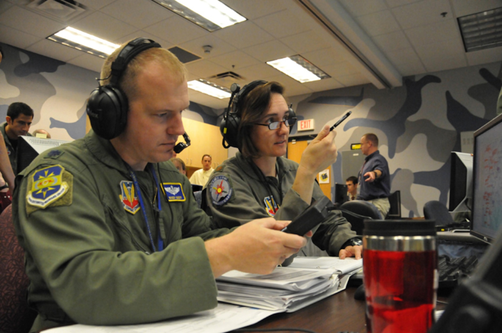 KIRTLAND AIR FORCE BASE, N.M. -- Lt. Col. Brynt Query, senior exercise director for the 705th Combat Training Squadron, and Maj. Michele Boyko, 705th CTS and exercise director for Coalition Virtual Flag 09-4, compare data during the exercise Sept. 18 at the Distributed Mission Operations Center. Coalition Virtual Flag 09-4 was the first ever exercise to integrate four coalition forces and air assets, and U.S. joint forces in a virtual air battle spanning operational- and tactical-level warfare. (Air Force photo by Ken Moore)