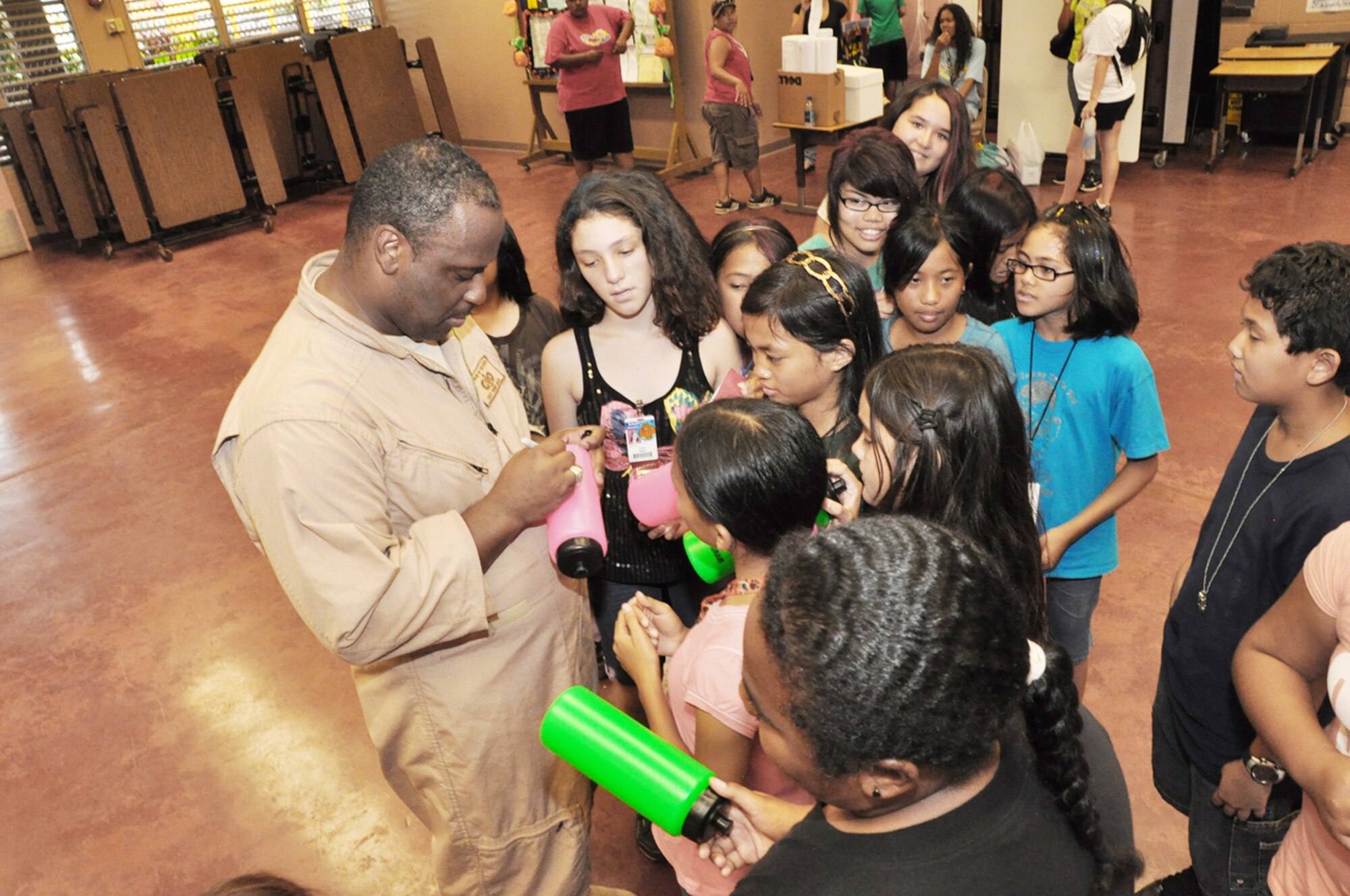 Tech. Sgt. Terry Grace signs autographs for the students of Kaleiopuu elementary School Oct. 22, 2009, in Waipahu, Hawaii. The Band of the Pacific-Hawaii peformed as part of Red Ribbon Week that is aimed at reinforcing children's decisions to stay away from drugs and make positive decisions in life. Sergeant Grace is a band bass guitarist. (U.S. Air Force photo/Tech. Sgt. Cohen A. Young)