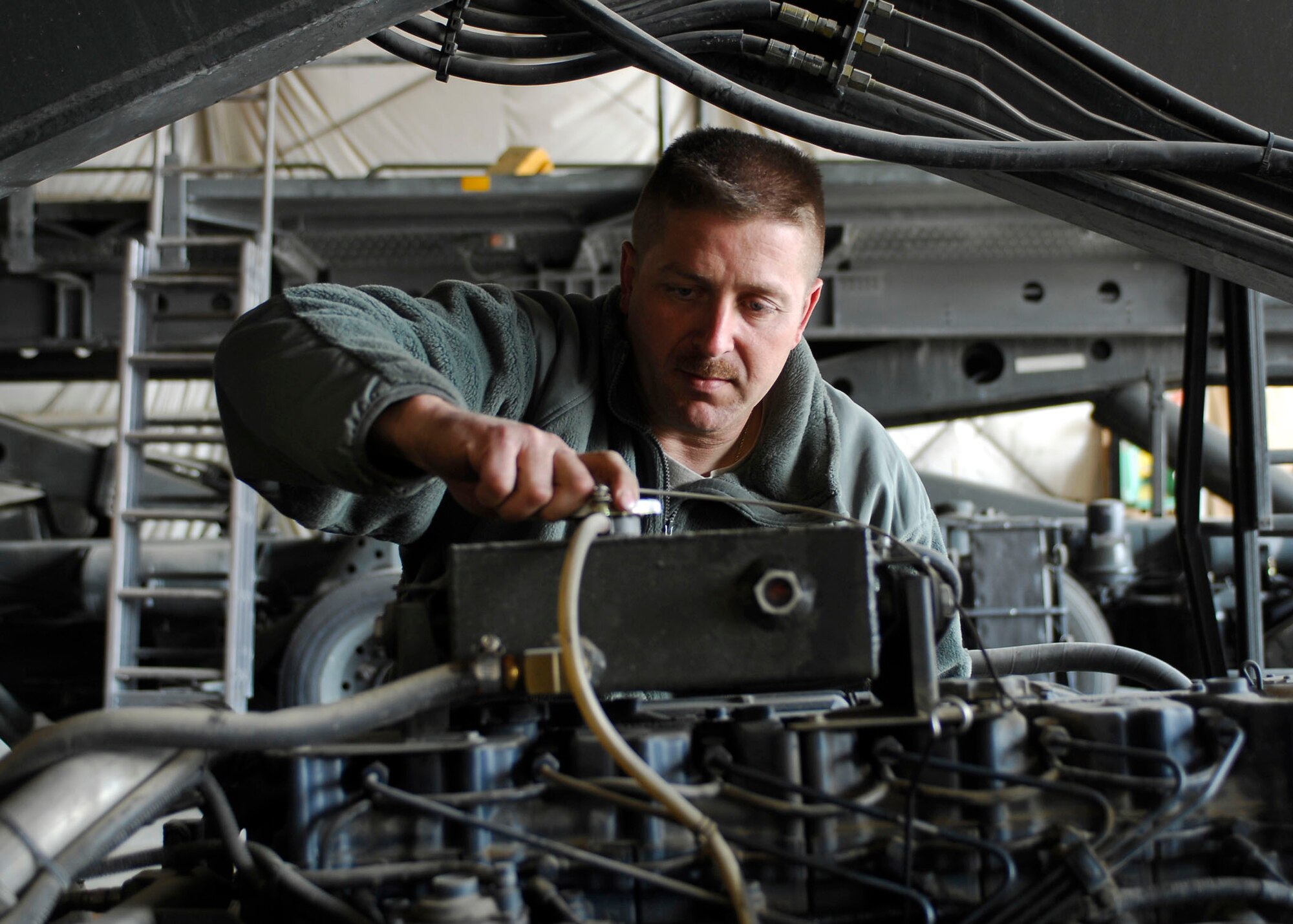 BAGRAM AIRFIELD, Afghanistan -- Tech. Sgt. Marco Hoffman, noncommissioned officer-in-charge of the Material Handling Equipment Shop from the 455th Expeditionary Logistics Readiness Squadron, checks for cracks on the engine during an inspection Oct. 28, 2009.  The 455th ELRS is responsible for fuels, vehicle maintenance, logistics planning, passenger terminal operations and air terminal operations.  Sergeant Hoffman is deployed from McChord Air Force Base, Wash., and hails from Cincinnati, Ohio.  (U.S. Air Force photo/Senior Airman Felicia Juenke)