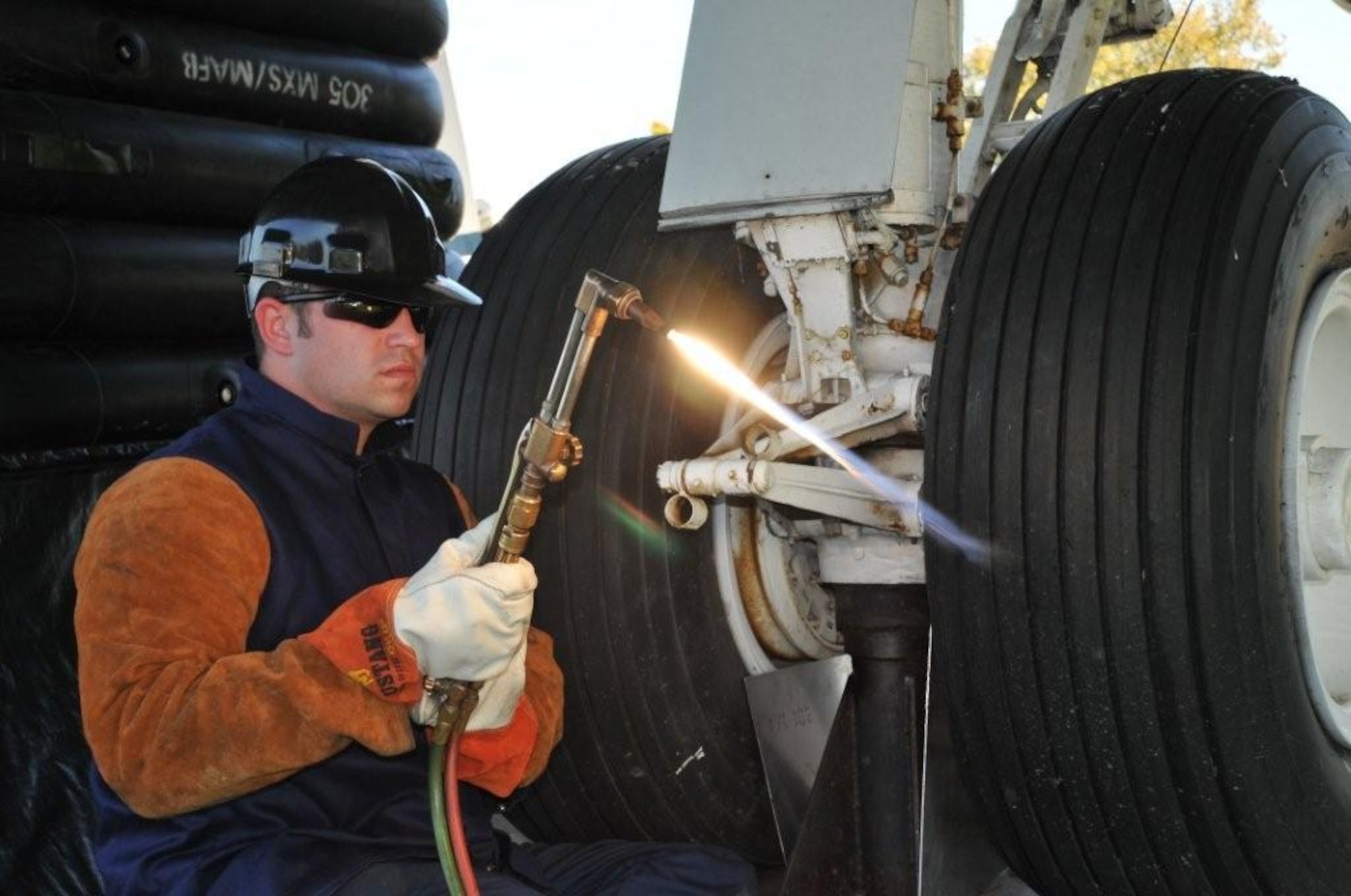 Senior Airman Shane Shepperson adjusts the flame on his acetylene torch prior to cutting the landing gear mount at the traffic circle here Oct. 22. Airman Sepperson and other members of the 305th and 514th maintenance groups will be renovating the C-118 Liftmaster that guards the McGuire passenger terminal throughout the next 10 months. (U.S. Air Force photo/Pascual Flores). 