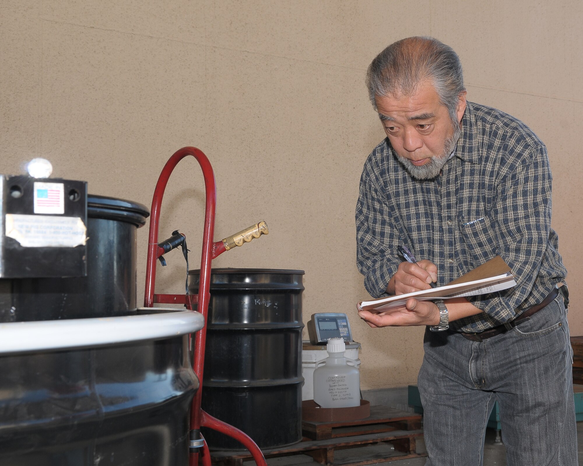 YOKOTA AIR BASE, Japan -- Naoki Kusunoki, 374th Civil Engineer Squadron assistant hazardous waste storage manager, writes down the tracking number on a barrel of hazardous waste Oct. 27. A team of inspectors will scour the base Nov. 2-6 as part of the 2009 Internal Environmental Safety Occupational and Health Compliance Assessment Management Program audit. (U.S. Air Force photo/Airman 1st Class Sean Martin)