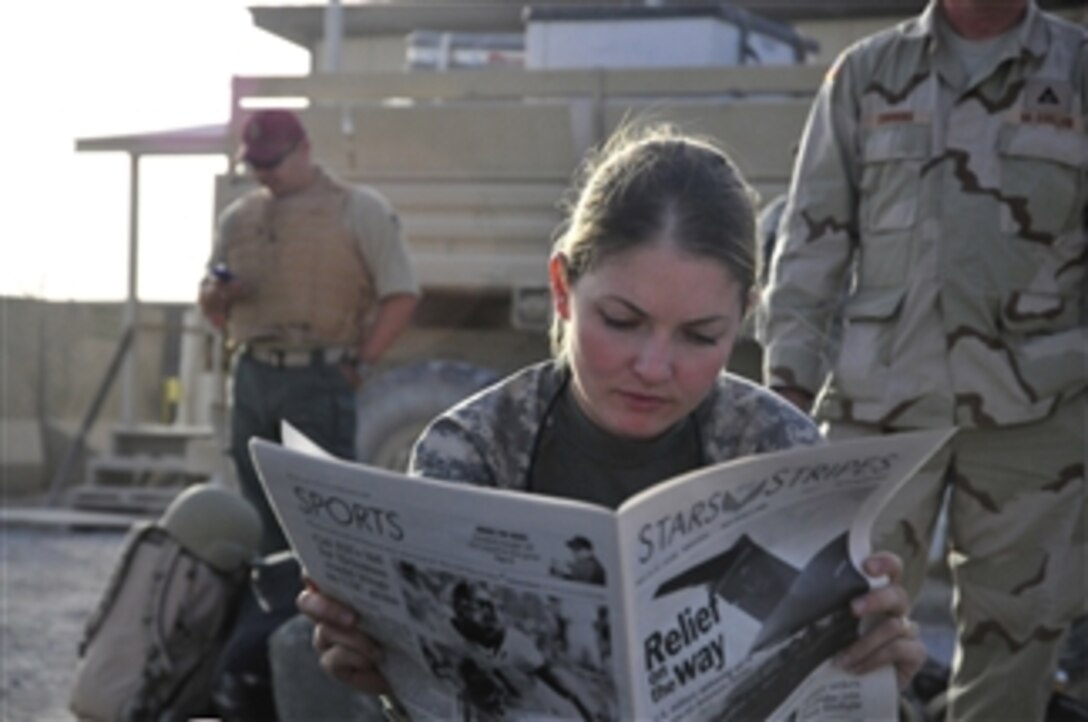 U.S. Army 1st Lt. Tracy Tyson, assigned to the 5th Brigade, 2nd Infantry Division, reads a newspaper at Kandahar Airfield, Afghanistan, while waiting for a flight to Forward Observation Base Wolverine on Oct. 5, 2009.  