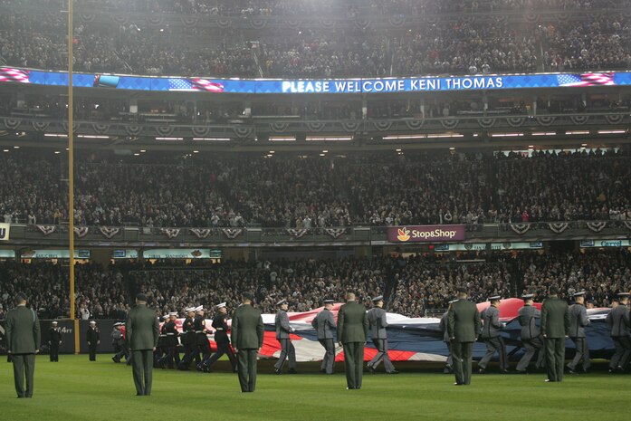 Marines, sailors, airmen, soldiers and West Point cadets unfurl an outfield-sized American Flag across Yankee Stadium prior to the first game of the World Series, Oct 28, New York. The ceremony honored military veterans.(Official Marine Corps photo by Sgt. Randall A. Clinton)
