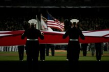 Marines, sailors, airmen, soldiers and West Point cadets unfurl an outfield-sized American Flag across Yankee Stadium prior to the first game of the World Series, Oct 28, New York. The ceremony honored military veterans.(Official Marine Corps photo by Sgt. Randall A. Clinton)