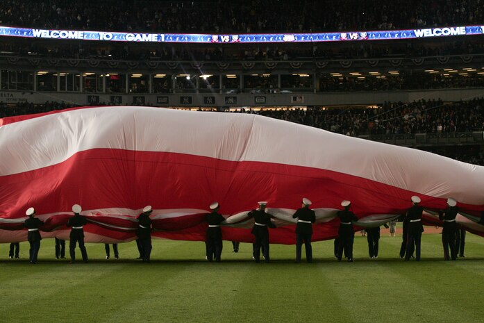 Marines, sailors, airmen, soldiers and West Point cadets unfurl an outfield-sized American Flag across Yankee Stadium prior to the first game of the World Series, Oct 28, New York. The ceremony honored military veterans.(Official Marine Corps photo by Sgt. Randall A. Clinton)