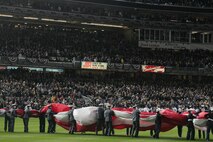 Marines, sailors, airmen, soldiers and West Point cadets unfurl an outfield-sized American Flag across Yankee Stadium prior to the first game of the World Series, Oct 28, New York. The ceremony honored military veterans.(Official Marine Corps photo by Sgt. Randall A. Clinton)