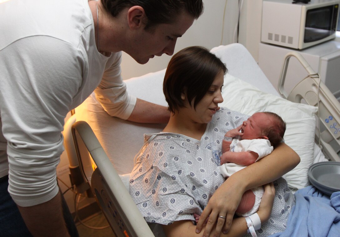 Lance Cpl. Alicia Oneil, administrative clerk, Instillation Personnel Administrative Center, Marine Corps Base Camp Pendleton, holds her newborn baby, 8-pound, 2-ounce Cain Hutcherson while the father, William Hutcherson comforts them at Naval Hospital, Camp Pendleton, Oct. 28. The baby was delivered two days earlier in the passenger side of his parents' car at the San Luis Rey gate by base Police Officers Rafael Moreno, Marcos Nieves and other Provost Marshal’s Office personnel.