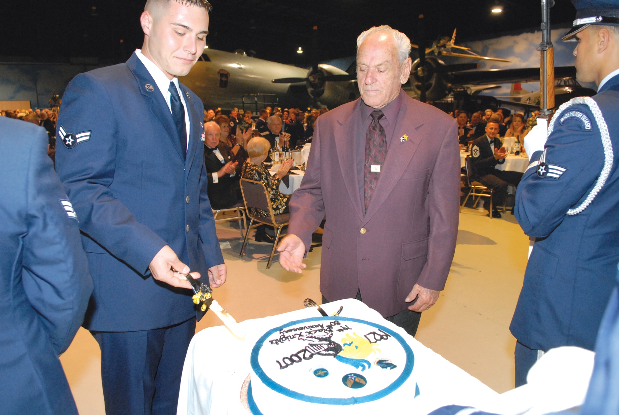 Airman First Class Josh Wullenweber, assigned to the 19th ARG April 30, 2006,  and MSgt (1st Sgt Ret) Howard Genthner, enlisted in February 1949 and retired in 1969, cut the 80th birthday cake at the ball Friday night as the youngest and most senior. U. S. Air Force photo by Ray Crayton
