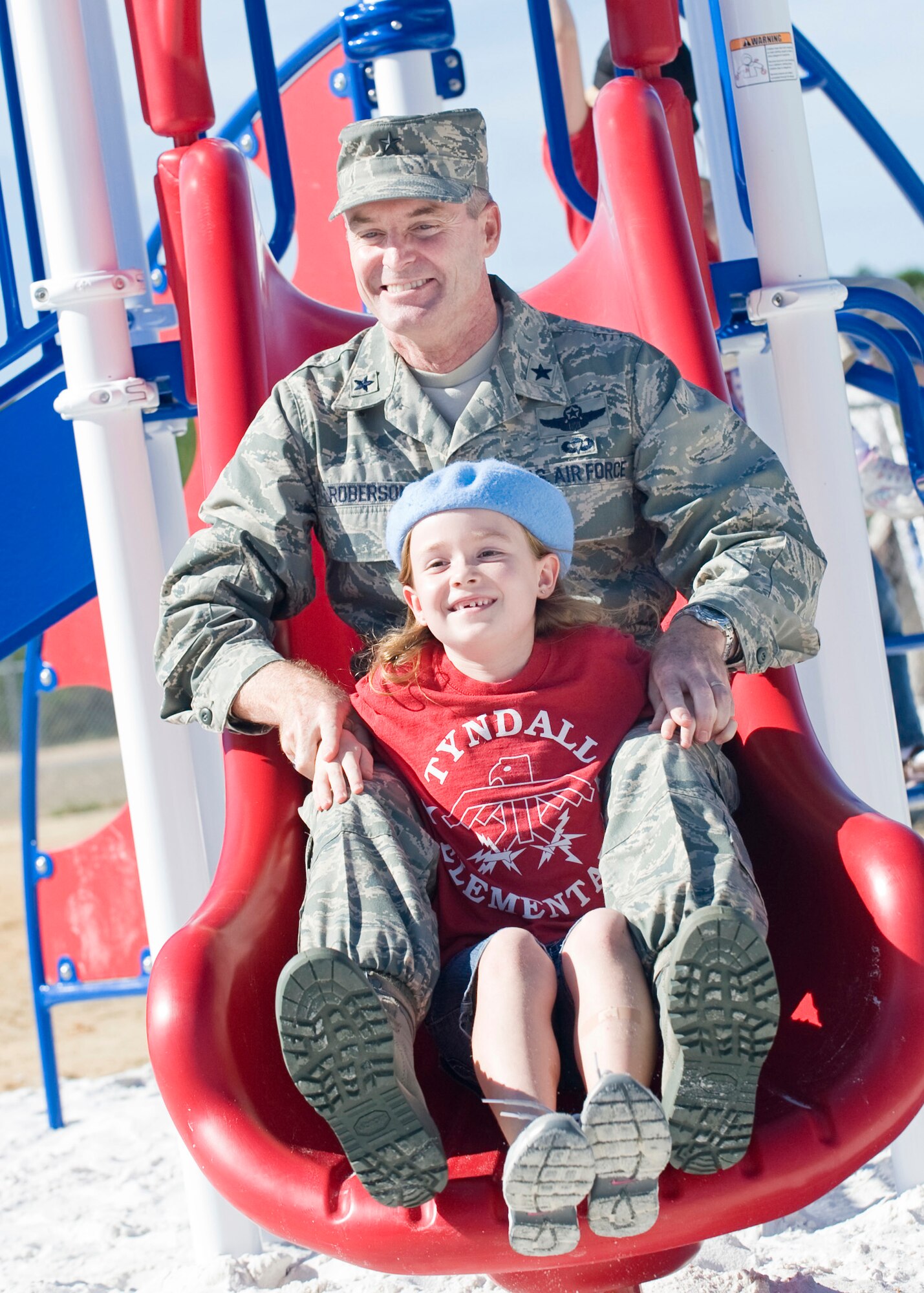 Brig. Gen. Darryl Roberson, 325th Fighter Wing Commander, and Zoey Van Vleet, Tyndall Elementary student, slide down newly installed playground equipment at Tyndall Elementary after a ribbon cutting ceremony honoring the completion of a time critical response action Oct. 29. (U.S. Air Force photo by Jonathan Gibson)
