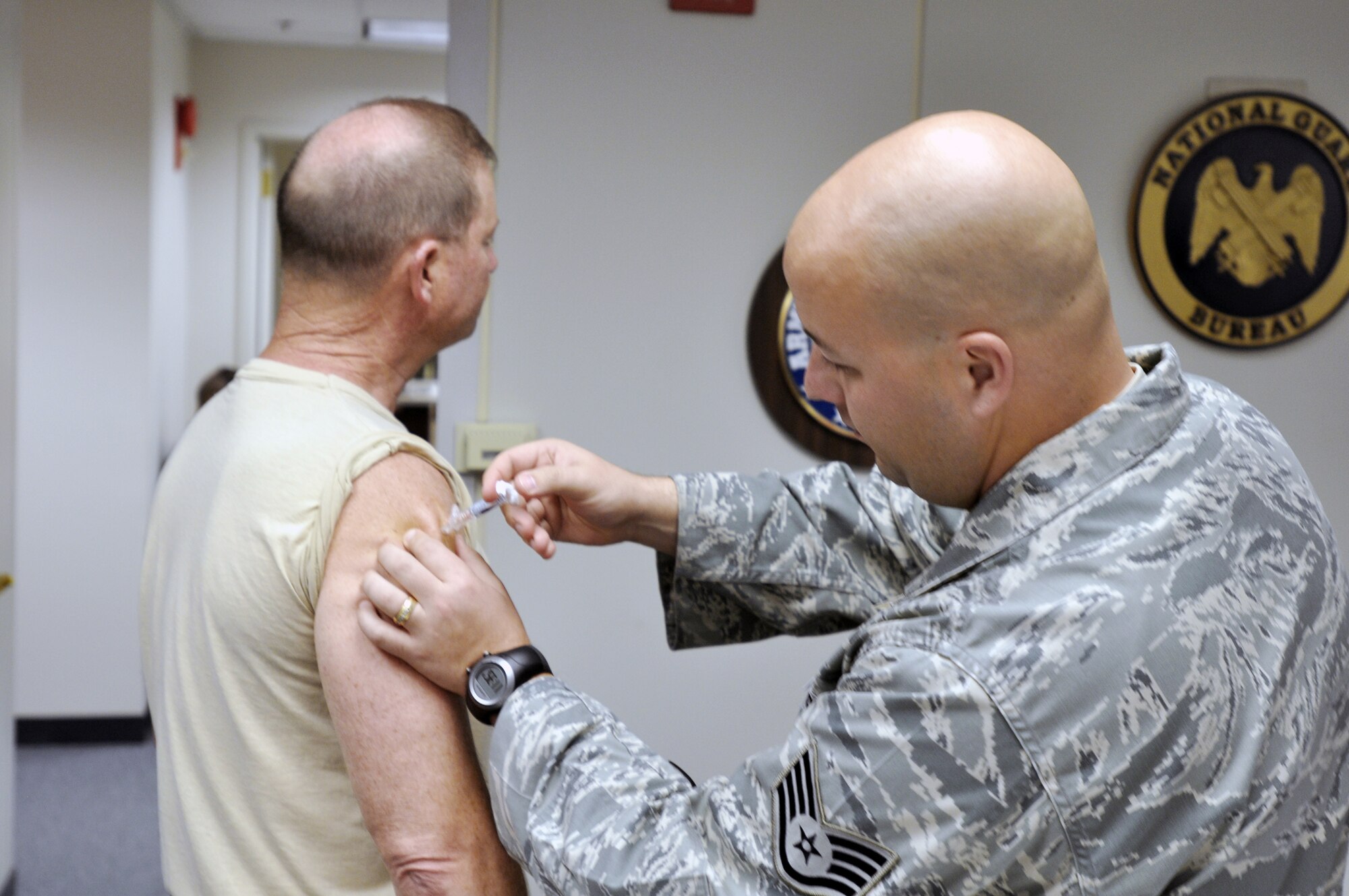 Army Sgt. Maj. Michael Mumford of the plans division of the National Guard Bureau in Arlington, Va., receives a seasonal flu shot from Staff Sgt. Shane Harper of the 579th Medical Group based during a vaccination campaign at the National Guard Bureau Oct. 23, 2009, at Bolling Air Force Base, D.C. The shot is mandatory for active-duty servicemembers. (U.S. Army photo/Staff Sgt. Jim Greenhill)