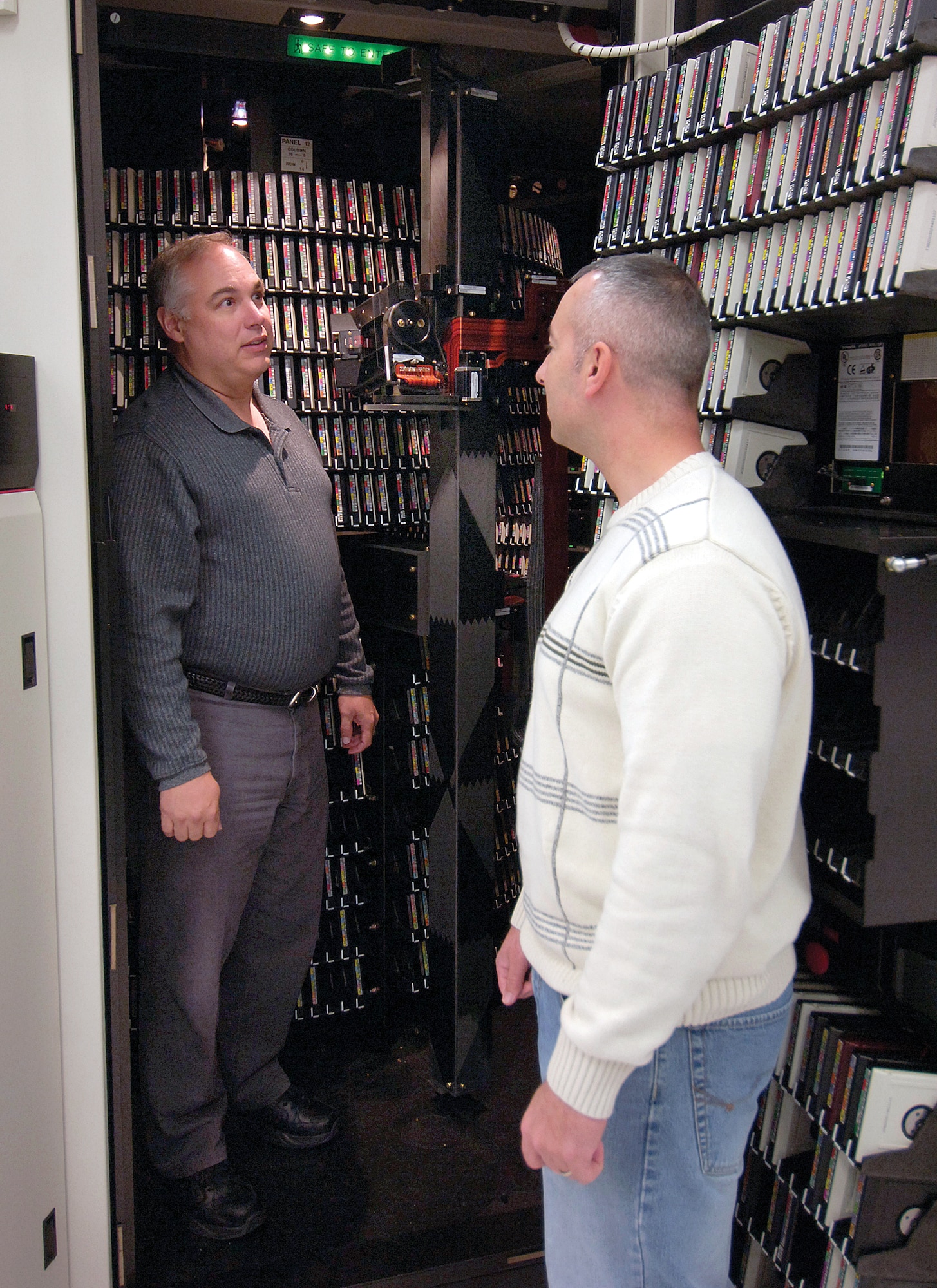 System analysts Chris Hollis, left, and Stephen Fischer, are surrounded by approximately 5,500 computer tapes inside a round library storage module operated by robotic arms that pull information when needed. Several of these modules cover the floor in DISA’s main computer room but disks are replacing the 10-year-old tape storage technology. DISA professionals anticipate the change within the next year. (Air Force photo by Margo Wright)