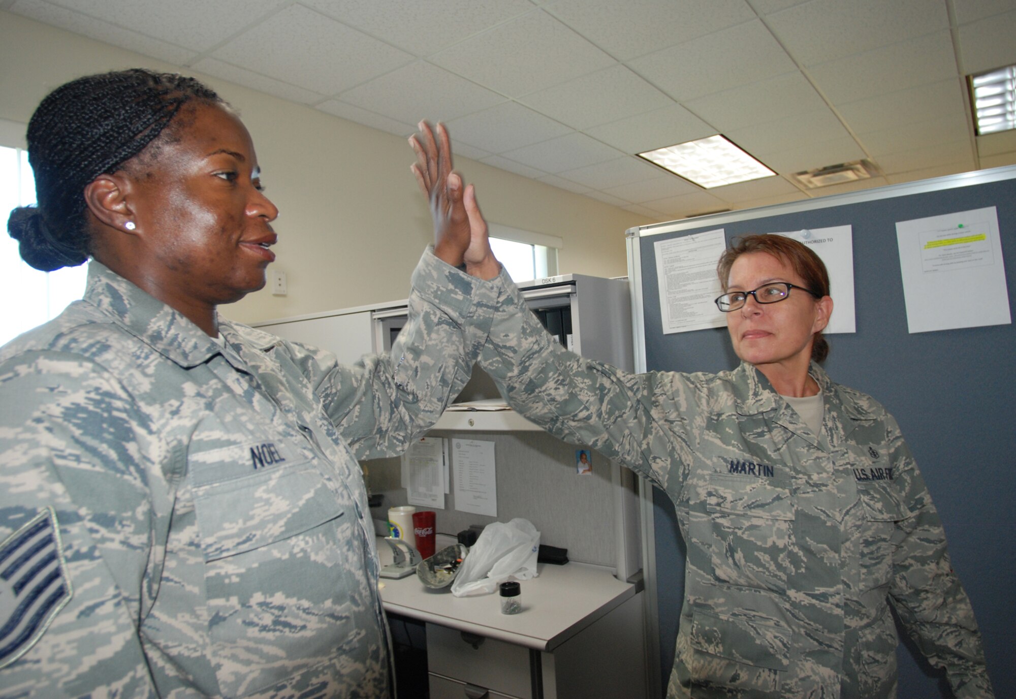 Technical Sgt. Esther Noel and Chief Master Sgt. Lori Martin, both from ASTS, high-five after their push-ups. PATRICK AIR FORCE BASE, Fla. - The office-wide participation motivates everyone to keep in shape with Air force physical fitness standards. (U.S. Air Force Photo/Leslie Kraushaar)