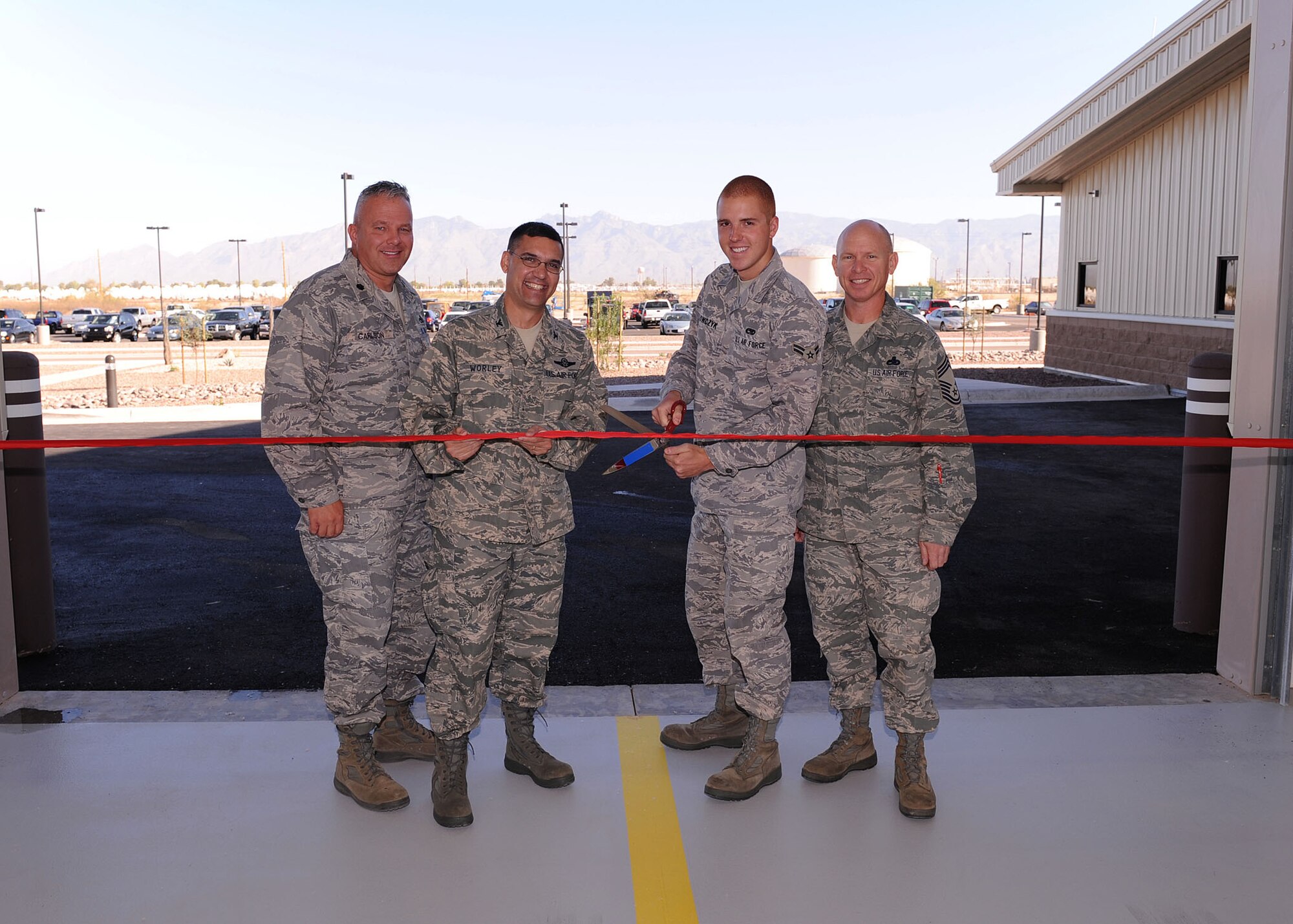 Lt. Col. David Carlson, 755th Aircraft Maintenance Squadron commander, Col. Dean Worley, 55th Electronic Combat Group commander, Airman 1st Class Chris Hekowcycz, and Chief Master Sgt. John Jasper, both from the 755th Aircraft Maintenance Squadron, cut the ribbon on the new $10.8M E-C130H "Compass Call" hangar here Oct. 2. The new facility is located between the 41st Electronic Combat Squadron and the 43rd Electronic Combat Squadron. The 755th AMXS will be able to use the hangar to remove the planes and people from Tucson's heat. (U.S. Air Force Photo/Senior Airman Jacqueline Hawkins)
