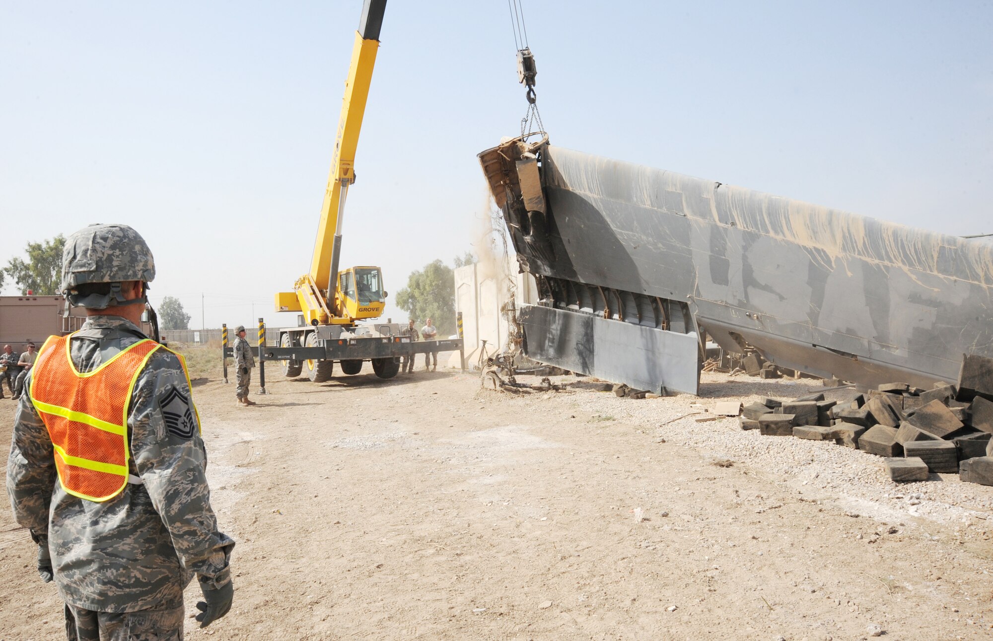 Senior Master Sgt. James Miller watches an Iraqi crane operator remove the left wing from a wrecked C-130 Hercules Oct. 27, 2009, at Sather Air Base, Iraq. The aircraft is believed to have been destroyed years ago after it crashed short of a runway outside the wire, without casualties. Several American and Iraqi airmen are working together to salvage parts for use as hands-on training aids for Iraqi aircraft maintainers at New Al Muthana Air Base. Sergeant Miller is the senior enlisted adviser for aircraft maintenance advisors assigned to the 321st Air Expeditionary Advisory Group and is deployed from Barksdale Air Force Base, La. He is a native of Warren, Ill. (U.S. Air Force photo/Tech. Sgt. Johnny L. Saldivar) 
