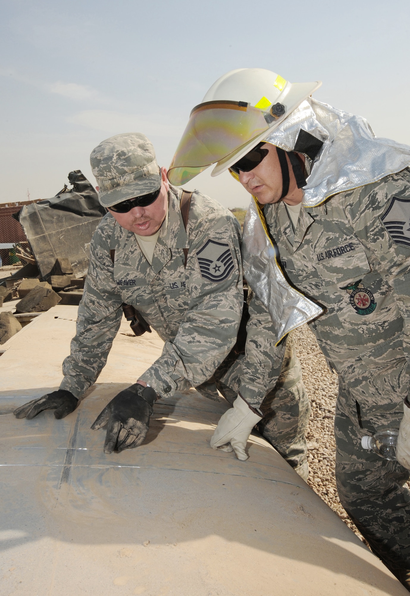 Master Sgt. Dellet Weaver (left) and Master Sgt. Marty Smith discuss how to remove the wing from a C-130 Hercules Oct. 27, 2009, at Sather Air Base, Iraq. The aircraft is believed to have been destroyed years ago after it crashed short of a runway outside the wire, without casualties. Several American and Iraqi airmen are working together to salvage parts for use as hands-on training aids for Iraqi aircraft maintainers at New Al Muthana Air Base. Sergeant Weaver is the production superintendent for aircraft maintenance advisers assigned to the 321st Air Expeditionary Advisory Group. He is deployed from Little Rock Air Force Base, Ark. and hails from Grafton, W.Va. Sergeant Smith is the assistant fire chief assigned to the 447th Expeditionary Civil Engineer Squadron and is deployed from the 132nd Fighter Wing of the Iowa Air National Guard. He is a native of Ankeny, Iowa. (U.S. Air Force photo/Tech. Sgt. Johnny L. Saldivar)