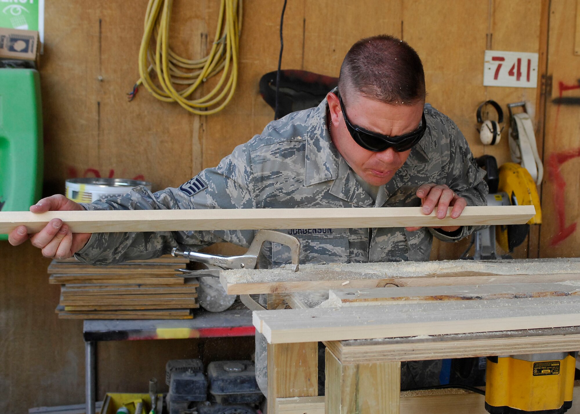 BAGRAM AIRFIELD, Afghanistan -- Staff Sgt. Troy Jorgenson, an engineering assistant from the 455th Expeditionary Civil Engineering Squadron, blows excess pieces of plywood so he can inspect it Oct. 29, 2009.  The wood will be used as picture frames for the wing headquarters building.  Sergeant Jorgenson is deployed from the Nevada Air National Guard's 152nd CES, and hails from Reno, Nev.  (U.S. Air Force photo/Senior Airman Felicia Juenke)