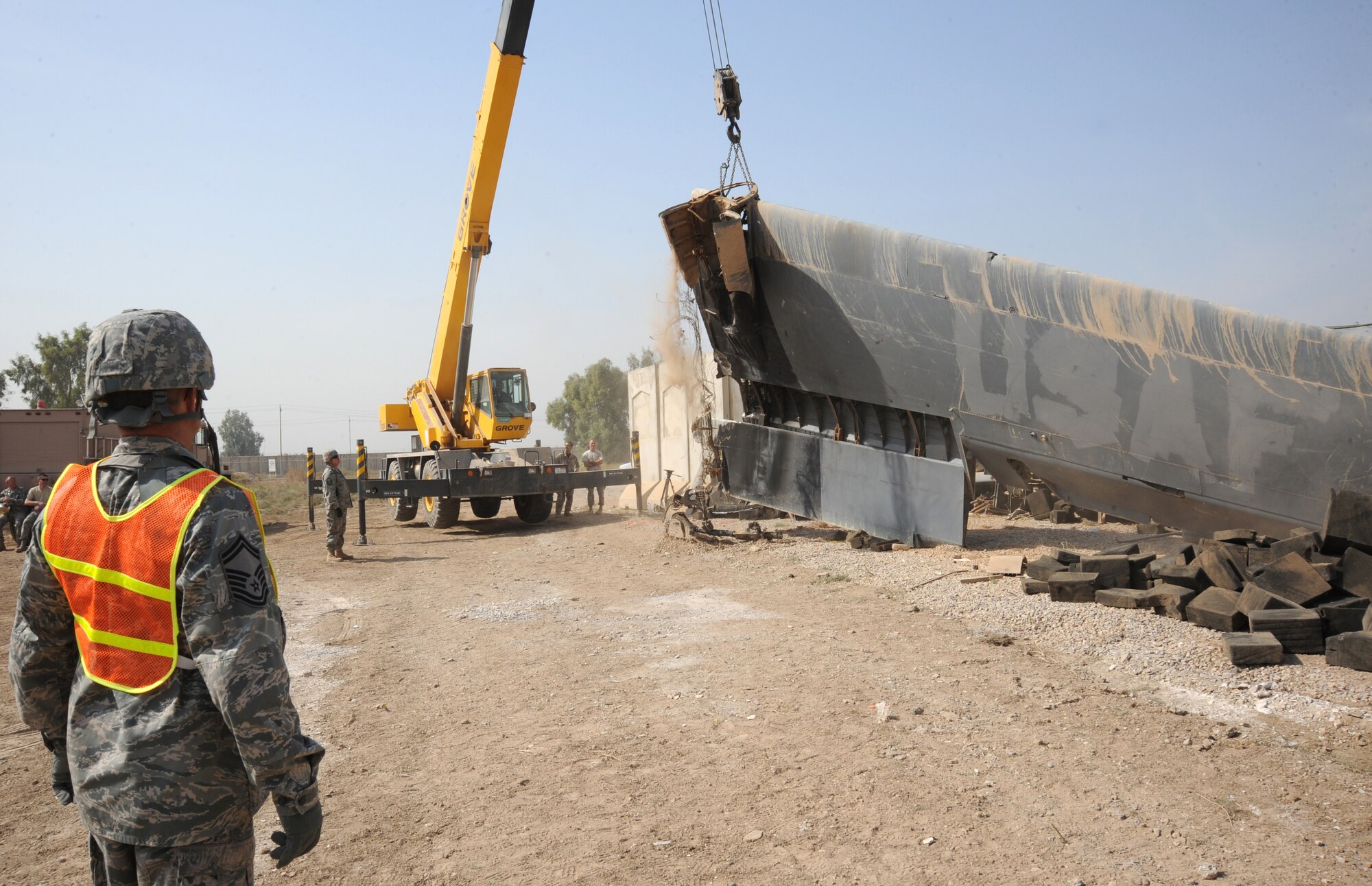 SATHER AIR BASE, Iraq -- Air Force Senior Master Sgt. James Miller, senior enlisted advisor for aircraft maintenance advisors assigned to the 321st Air Expeditionary Advisory Group, watches an Iraqi crane operator remove the left wing from a wrecked C-130 Oct. 27, 2009. The aircraft is believed to have been destroyed years ago after it crashed short of a runway outside the wire, without casualties. Several American and Iraqi Airmen are working together to salvage parts for use as hands-on training aids for Iraqi aircraft maintainers at New Al Muthana Air Base. Sergeant Miller is deployed from Barksdale Air Force Base, La., and is originally from Warren, Ill. (U.S. Air Force photo/Tech. Sgt. Johnny L. Saldivar)