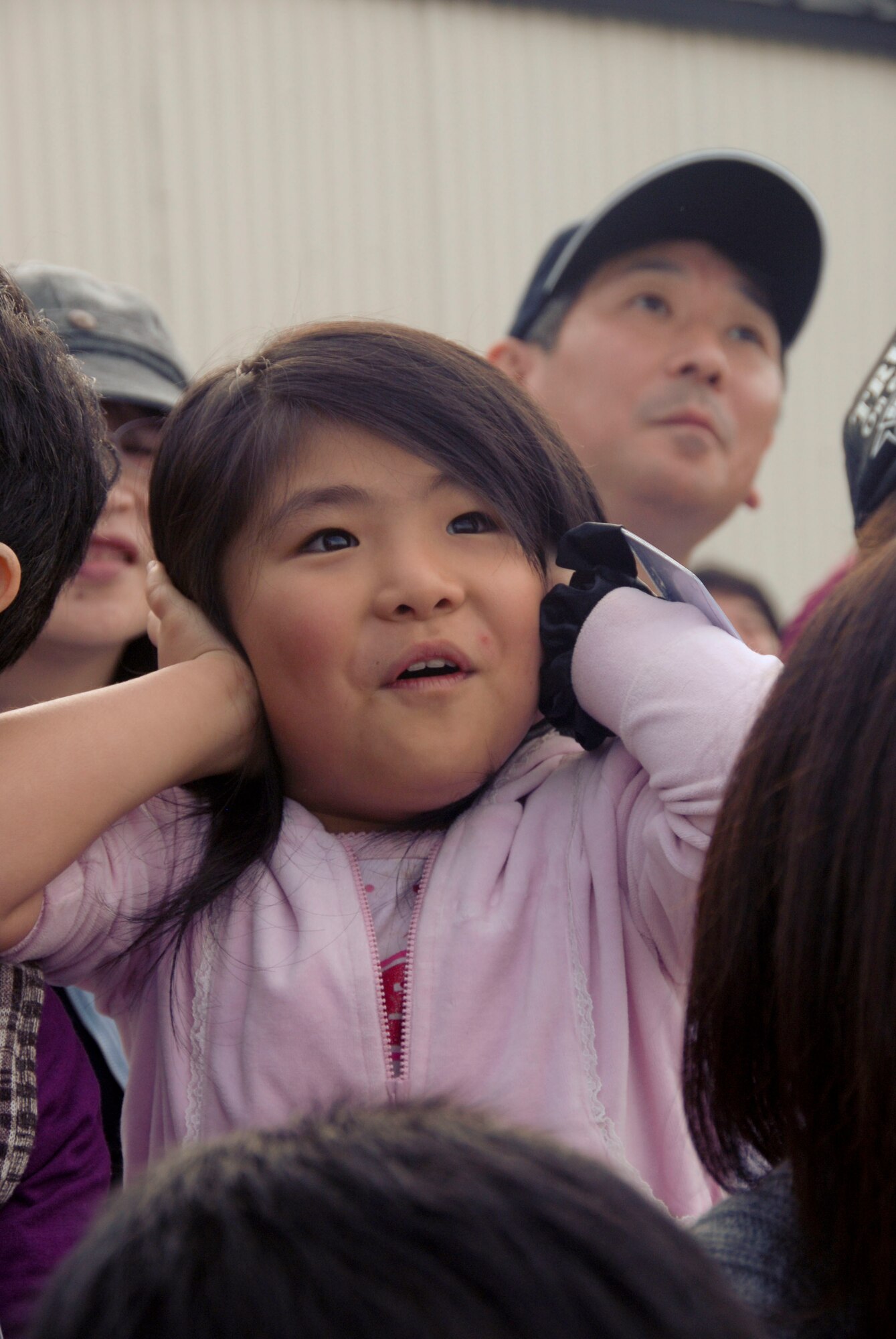 MISAWA AIR BASE, Japan -- A young girl protects her ears from the noise of the U.S. Air Force Thunderbirds jets during the Misawa Air Fest Oct. 18, 2009. More than 50 Japanese children, to include those with special needs, and their parents were invited to take part in a unique community relations event that included viewing the air show, playing at the Weasel's Den and meeting the U.S. Air Force Thunderbirds. (U.S. Air Force photo/Staff Sgt. Rachel Martinez)