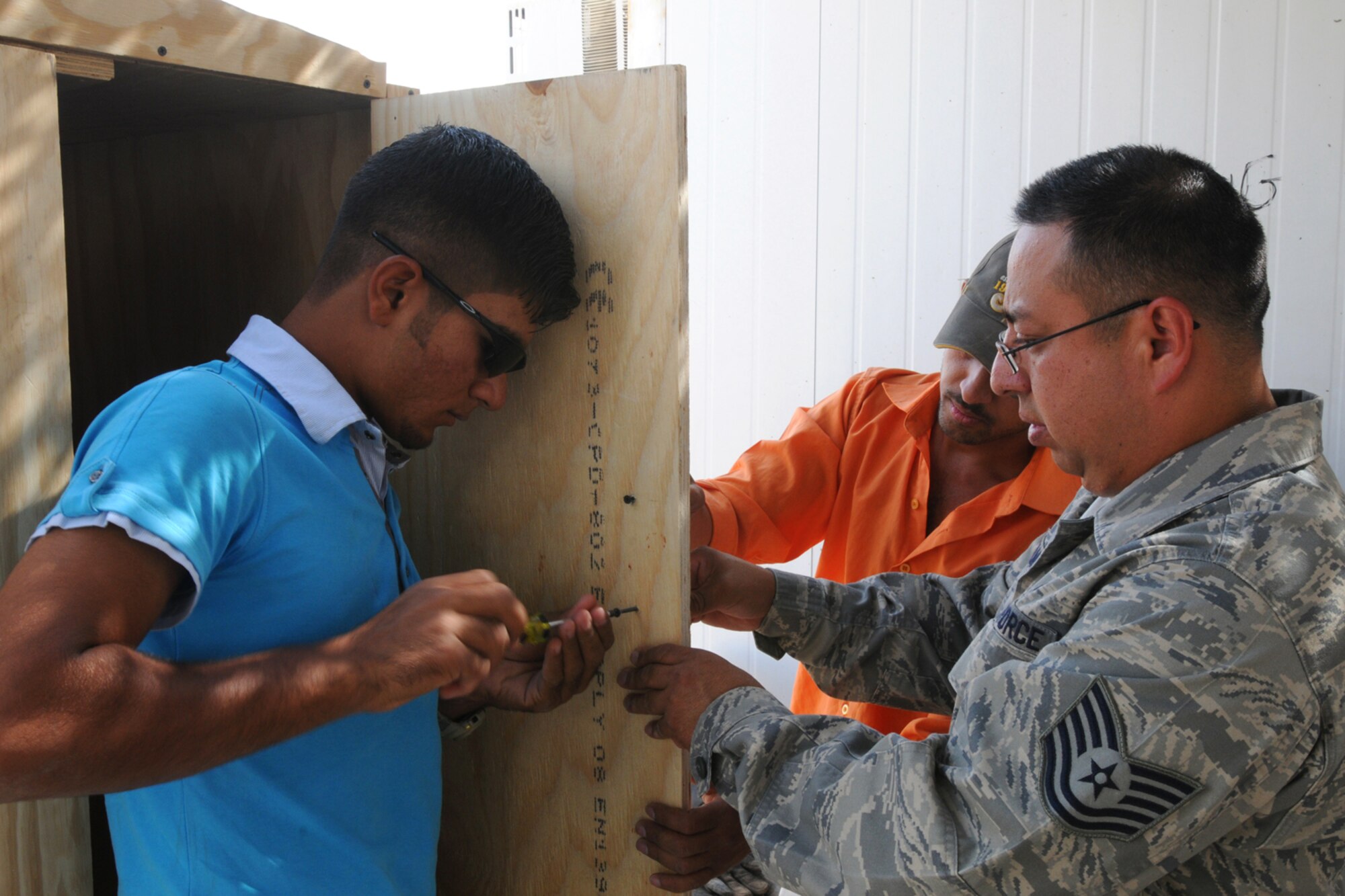 KIRKUK REGIONAL AIR BASE, Iraq - Tech. Sgt. Alexander Almonte, 506th Expeditionary Civil Engineer Squadron, utilities systems craftsman, helps guide Nabil Salman and Abdqader Umer, local workers, who assembled a cabinet by hand here Oct. 17.  The 506th ECES works with local nationals who are employed by a local contractor on base to develop their skills which allow them to work and complete job orders.  Sergeant Almonte is deployed here from the 446th CES, McChord Air Force Base, Wash.  (U.S. Air Force photo/Staff Sgt. Daniel Martinez)