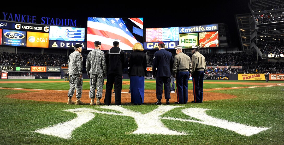 U.S. Army Sgt. Mary Kay Messenger, center, sings "God Bless America" while veterans U.S. Air Force Staff Sgt. Jesse Schrader and U.S. Navy Petty Officer 2nd Class Damion Salabie stand at attention during the first game of the World Series between the Philadelphia Phillies and the New York Yankees at Yankee Stadium in New York, Oct. 28, 2009.
