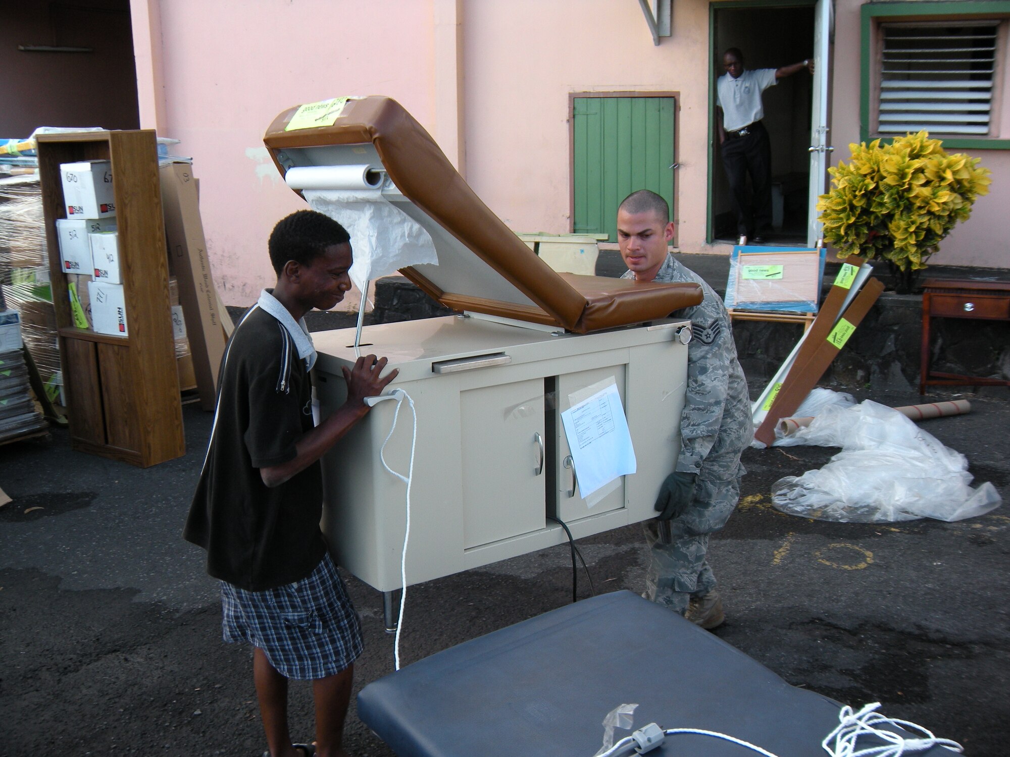 Staff Sgt. Daniel Osorio, 52nd Airlift Squadron C-130 Hercules crew chief, helps a local man move an examination table during an Oct. 30 delivery of humanitarian supplies to the Caribbean island of St. Vincent. The supplies, donated by the Wausau, Wis. based Good News Project, included hospital and mental health supplies as well as desks, paper and school supplies to various locations on the island. The Air Force Reserve aircraft transported the supplies under the Denton Amendment, which authorizes U.S. military aircraft via Congress to airlift humanitarian supplies based on space availability and other factors. Sergeant Osorio is an Active Duty Airman associated with the AF Reserve's 302nd Airlift Wing based at Peterson Air Force Base, Colo. (U.S. Air Force photo/Staff Sgt. Stephen J. Collier)