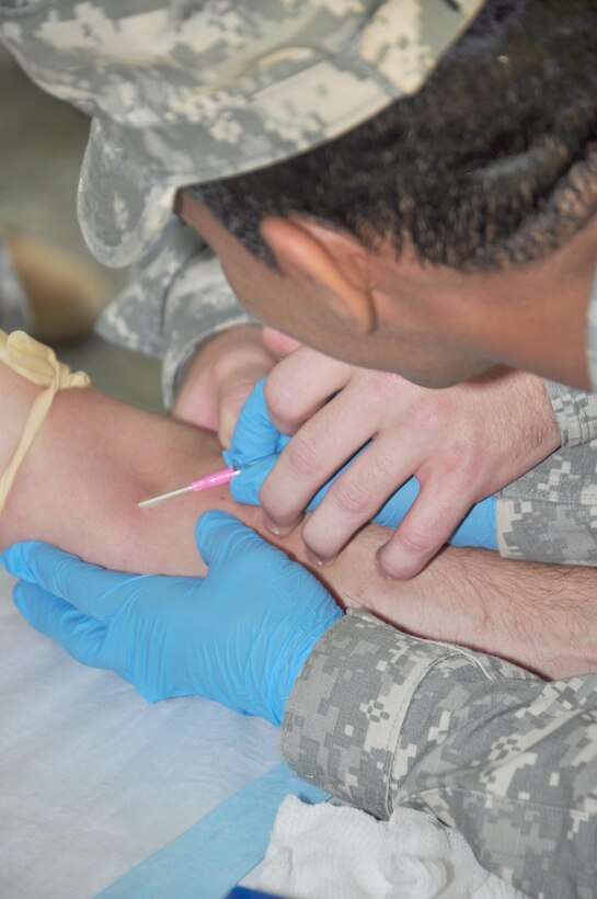 SOTO CANO AIR BASE, Honduras — Army Sgt. 1st Class Alicia Thomas, 1st Battalion, 228th Aviation Regiment, practicing inserting an IV into another soldier Oct. 28 at the base firing range during a three-day field training exercise. Soldiers from the 1st Battalion, 228th Aviation Regiment recently turned their focus from helicopter operations to some basic Soldier field training from Oct. 25 to 29. Some of the things taught during the training were: practicing recall procedures, setting up tents, radio communications, convoy operations, combat medicine, vehicle staging, wrecker operations, M-249 light machine gun familiarization and firing the M-249 at the range (U.S. Air Force photo/Staff Sgt. Chad Thompson).