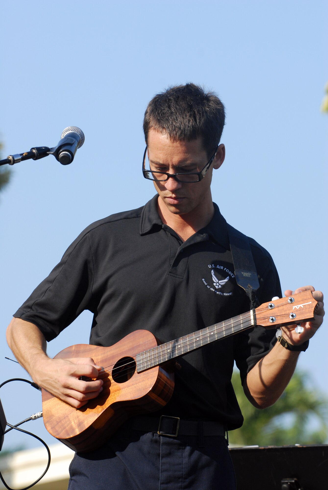 HICKAM AIR FORCE BASE, Hawaii -- Staff Sgt. Johnny Kukan, U.S. Air Force Band of the Pacific guitarist, tunes his ukulele before a performance for Hickam Elementary School students here, Oct. 29. Hickam, one of two elementary schools on base, was one of six schools the band performed for in support of Red Ribbon Week. Red Ribbon Week focuses on living and maintaining a drug free lifestyle. (U.S. Air Force photo/Senior Airman Gustavo Gonzalez)
