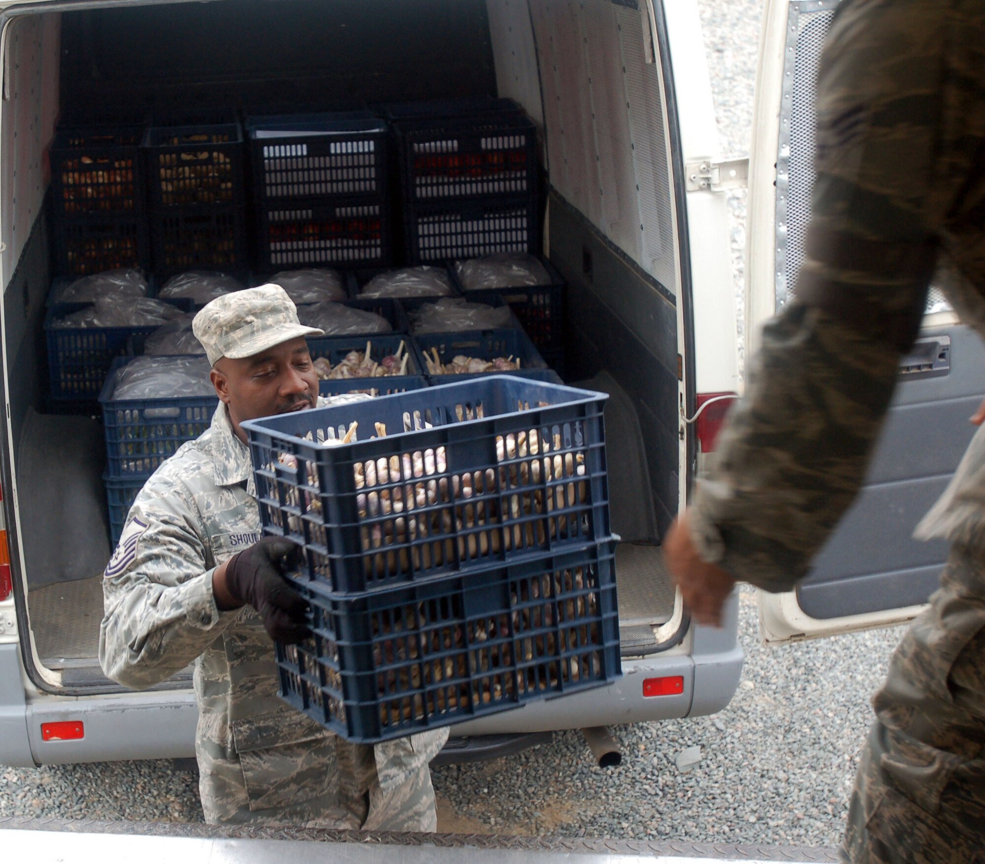 Master Sgt. John Shoulars passes crates of garlic during the delivery of the first set of local farm products Oct. 27, 2009, to the Transit Center at Manas, Kyrgyzstan. The delivery, which consisted of fresh fruits, vegetables and bakery products, was part of the efforts Airmen here are making to support more local businesses. Sergeant Shoulars is the sustainment flight chief for the 376th Expeditionary Force Support Squadron. (U.S. Air Force photo/Chief Master Sgt. James Dowell)