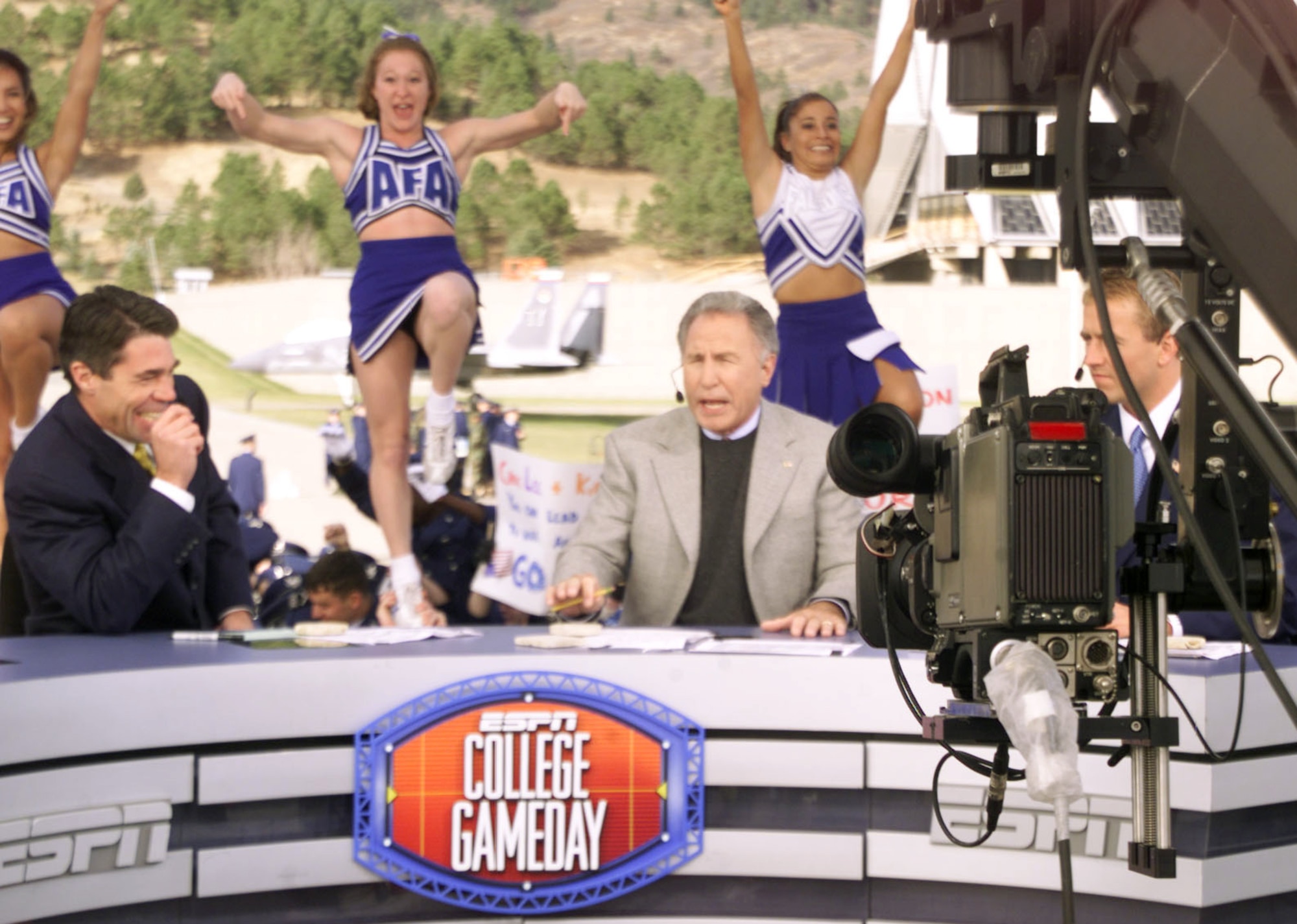 ESPN College GameDay host Chris Fowler, left, cracks up at the antics going on behind the set, while cohost Lee Corso is on-camera explaining why fans should "wait a minute" during their first live broadcast from the Academy Nov. 2, 2001. ESPN College GameDay returns to the Air Force Academy Nov. 7, and will broadcast live from the Terrazzo before for the Air Force-Army football game. The Academy cheerleaders in this photo are, left to right: Karen Jelke, Sabrina Kingston and Bernadette Lavarrada-Perez. (U.S. Air Force photo/John Van Winkle)