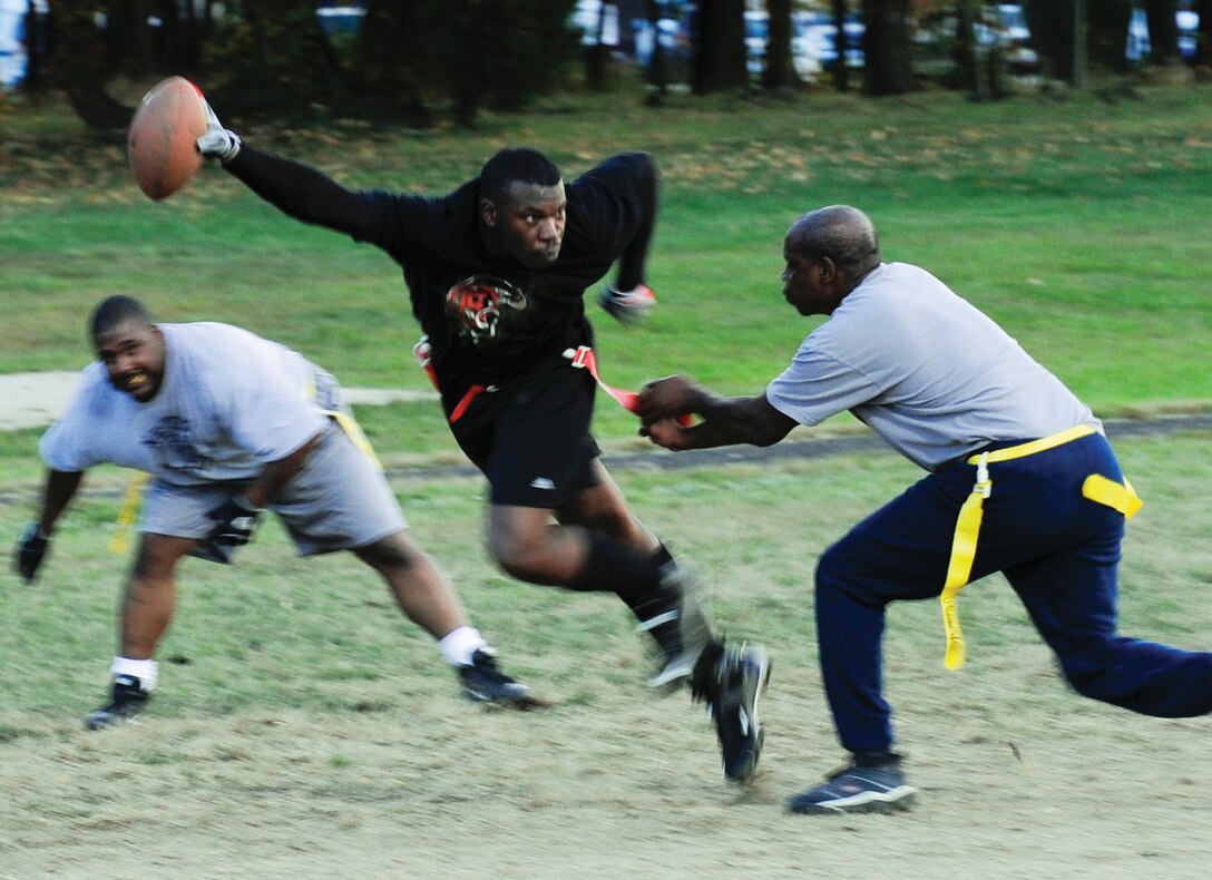 Timothy Gibbs, 316th Comptroller Squadron tight end, center, maneuvers his way through two 316th Civil Engineer Squadron defenders in an effort to gain extra yardage during a playoff game Oct. 22. The 316 CES came away with a 14-12 victory. During the Intramural Flag Football Championship game between 316 CES and 779th Medical Group Oct. 26, 316 CES won 13-6. (U.S. Air Force photo/ Staff Sgt. Keyonna Fennell)