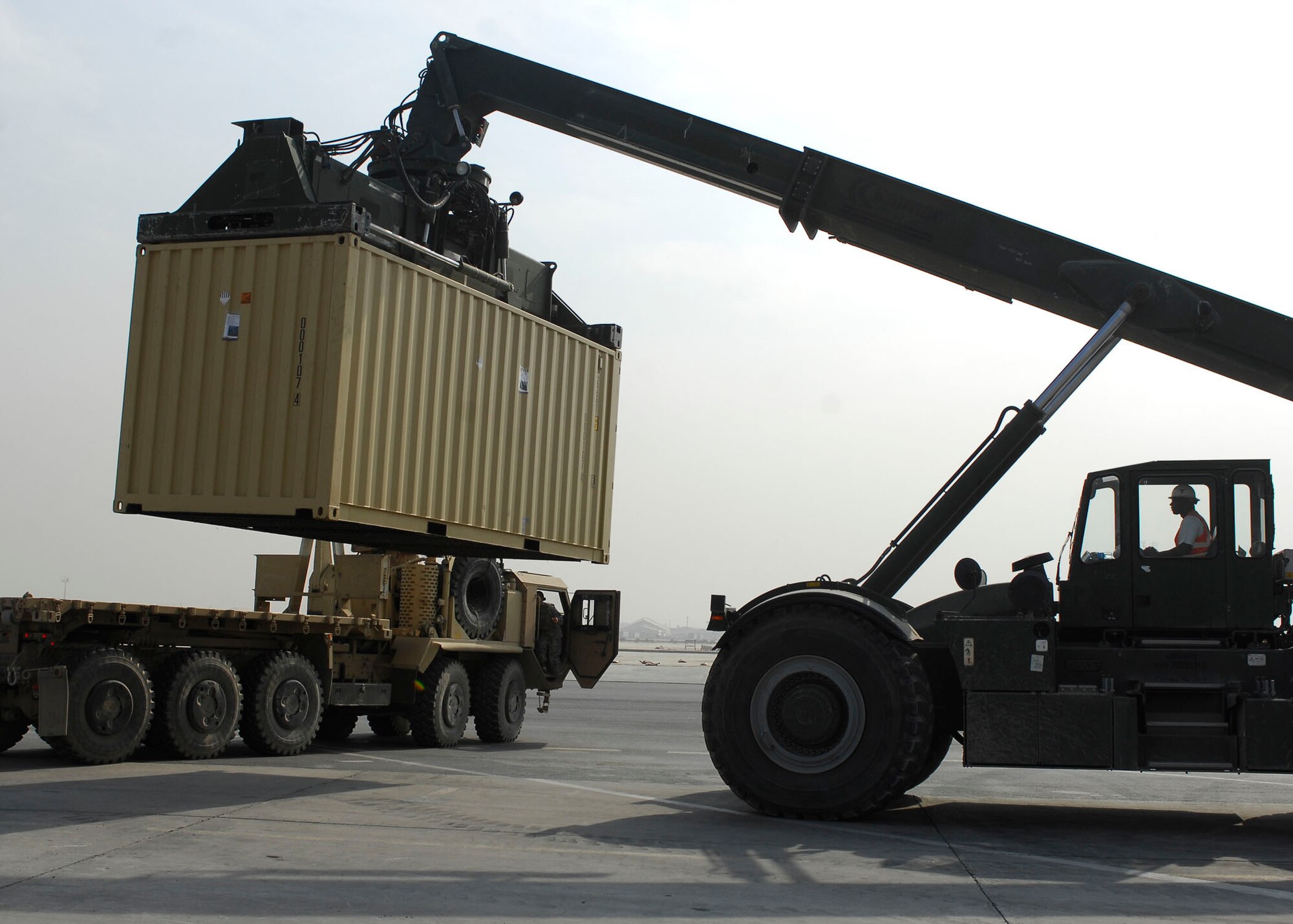 BAGRAM AIRFIELD, Afghanistan -- Mr. Randy Pryor, a civilian contractor, uses a rough terrain cargo handler to move shipping containers to a heavy expandable mobility tactical truck (HEMTT) Oct. 30, 2009.  The HEMTT is being used to transport the shipping containers to the Army's supply yard.  The shipping containers can be used for various things including offices or living quarters.  Mr. Pryor, a native of Sulphur Springs, Texas, said "I love supporting the military, that's why I'm here."  (U.S. Air Force photo/Senior Airman Felicia Juenke)