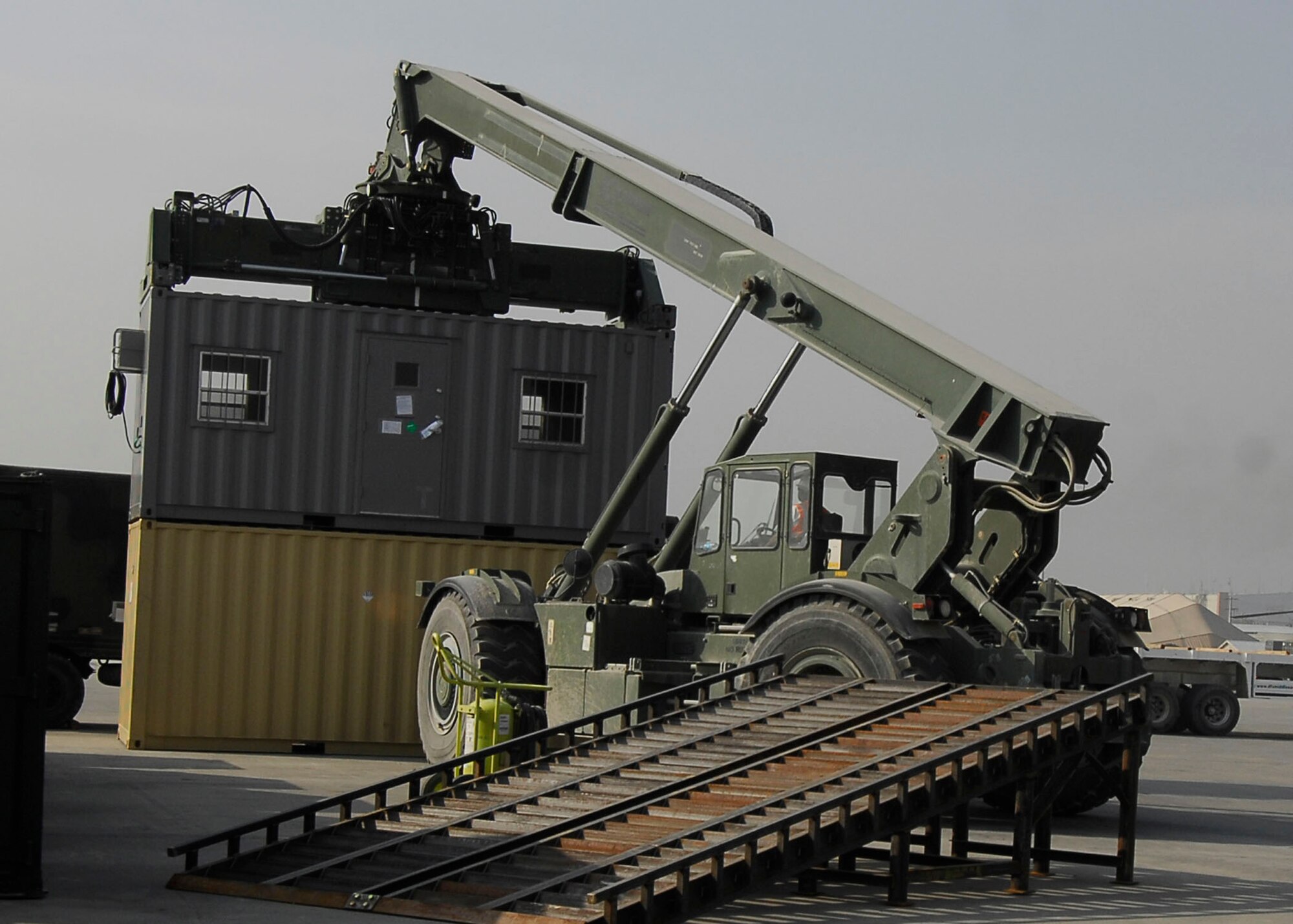 BAGRAM AIRFIELD, Afghanistan -- Mr. Randy Pryor, a civilian contractor, uses a rough terrain cargo handler to move shipping containers to a heavy expandable mobility tactical truck (HEMTT) Oct. 30, 2009.  The HEMTT is being used to transport the shipping containers to the Army supply yard.  The shipping containers can be used for various things including offices or living quarters.  Mr. Pryor, a native of Sulphur Springs, Texas, said "I love supporting the military, that's why I'm here."   (U.S. Air Force photo/Senior Airman Felicia Juenke)