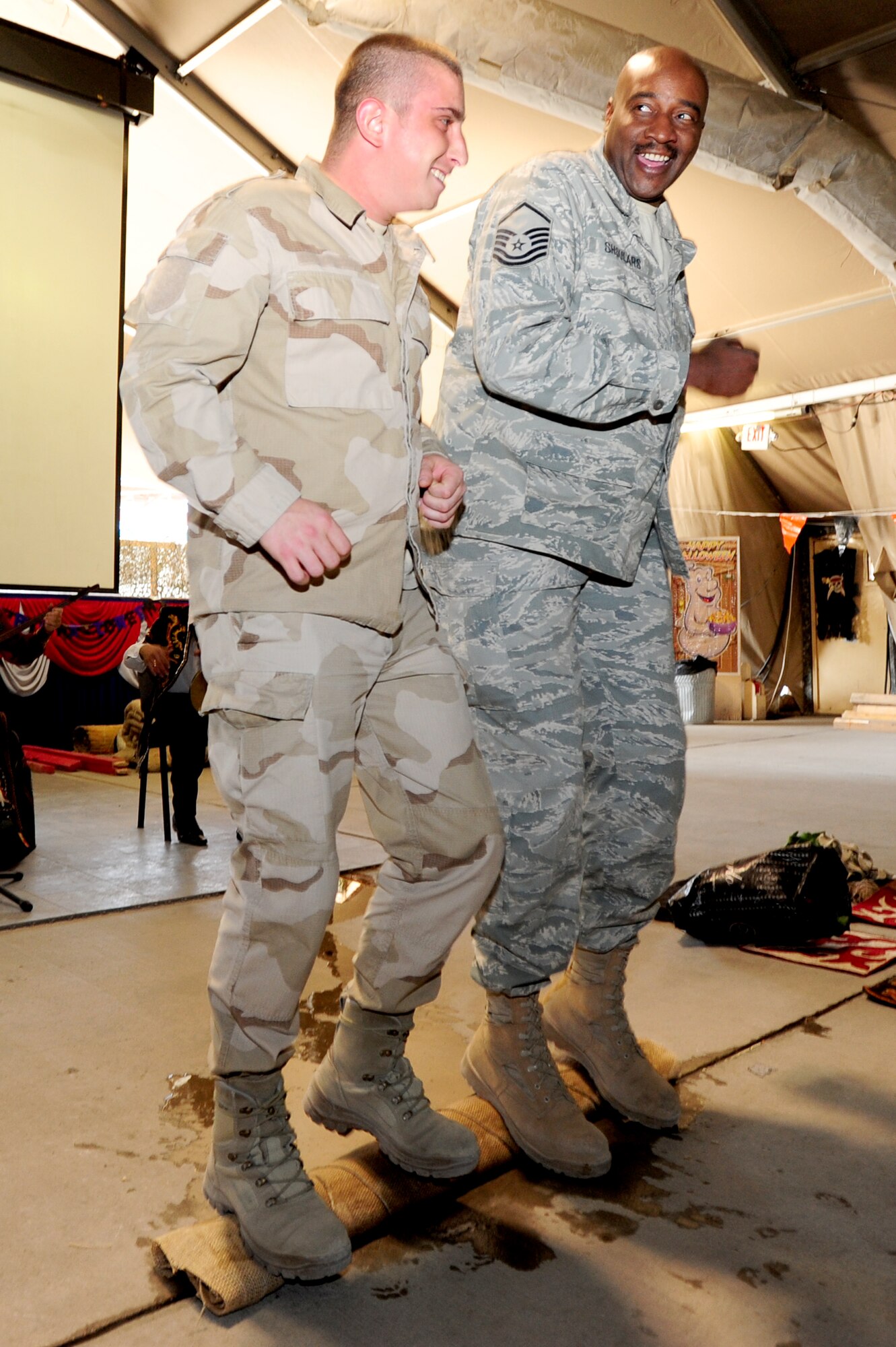 TRANSIT CENTER AT MANAS, Kyrgyzstan -- Master Sgt. John Shoulars, 376th Expeditionary Force Support Squadron sustainment flight chief, and a fellow Polish Airman, dance on a carpet to remove water during a Kyrgyz Culture Day at the Transit Center, Oct. 24, 2009. (U.S. Air Force photo/Senior Airman Steele C. G. Britton)