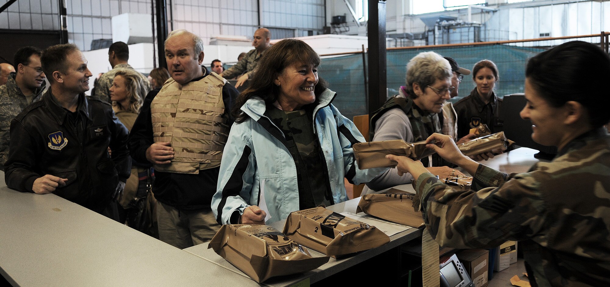 RAF MILDENHALL, England -- Honorary commanders of military units here receive their Meals, Ready to Eat before "deploying" to a mock Camp Kabul on base Oct. 29. These local dignitaries and their guests participated in the Team Mildenhall Honorary Commanders' Deployment Day to learn more about military deployments. MREs are vacuum-sealed, individual field rations used in combat or other field conditions where dining facilities are not available. (U.S. Air Force photo/Senior Airman Thomas Trower)