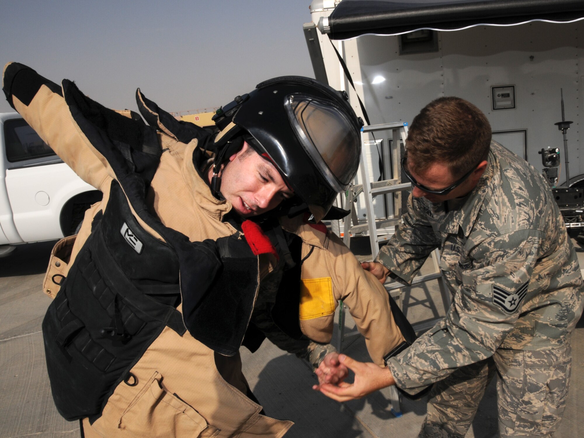 Senior Airman Ronald Abbate, 379th Expeditionary Contracting Squadron contingency contracting officer, tries on the Explosive Ordnance Disposal 9 bomb suit with the help of Staff Sgt. Neil Gertiser, 379th Expeditionary Civil Engineer Squadron EOD NCOIC during Flightline Fest, Oct. 29, 2009. Flightline Fest was an opportunity to showcase 379 AEW, joint and coalition aircraft, as well as base equipment to deployed servicemembers. Airman Abbate is deployed from Eielson Air Force Base, Alaska. Sergeant Gertiser is deployed from Lackland Air Force Base, Texas. Both are deployed in support of operations Iraqi Freedom and Enduring Freedom. (U.S. Air Force Photo/Tech. Sgt. Jason W. Edwards)