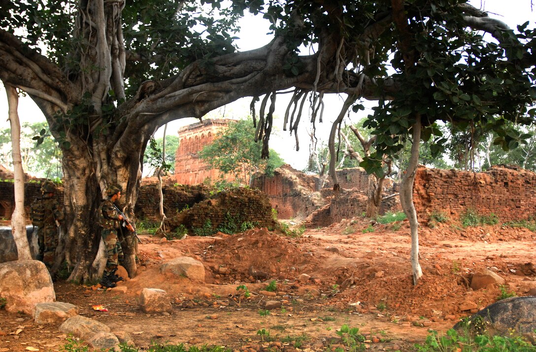 Two Indian army soldiers wait outside of a village before moving in to secure it during a joint exercise with U.S. soldiers on Camp Bundela, India, Oct. 25, 2009. The 150-year-old village was discovered covered by underbrush and cleared for the exercise to practice clearing skills.