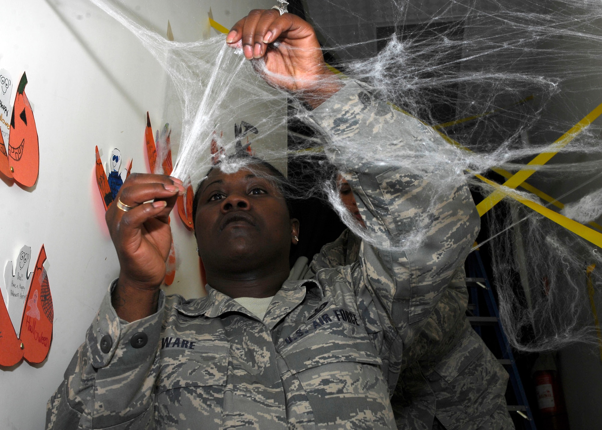 BAGRAM AIRFIELD, Afghanistan -- Staff Sgt. April Roseborough Ware, a non-appropriated funds accountant from the 455th Expeditionary Force Support Squadron, hangs fake spider webs in a stairwell, Oct. 31, 2009.  Sergeant Ellis along with multiple volunteers decorated a building for Halloween, where there will be a live band, food, beverages, and many games.  The building is used to boost morale of Armed Forces deployed to Bagram Airfield.  Sergeant Ware is deployed from Moody Air Force Base, Ga., and hails from Miami, Fla.  (U.S. Air Force photo/Senior Airman Felicia Juenke)