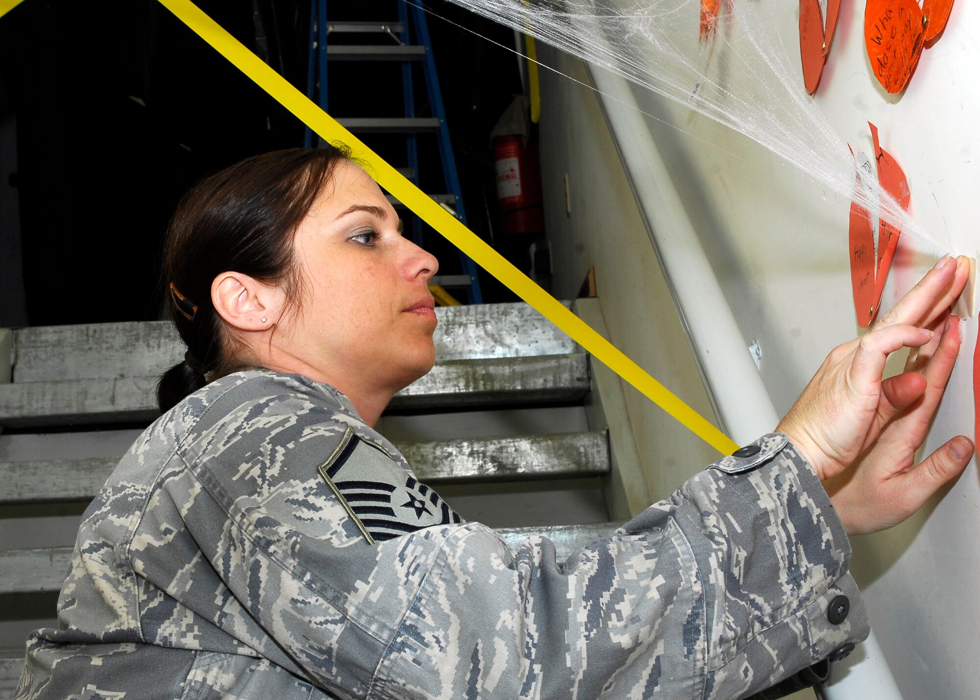 BAGRAM AIRFIELD, Afghanistan -- Master Sgt. Jennifer Ellis, the 455th Expeditionary Force Support Squadron Services Flight chief, decorates for Halloween by hanging fake spider webs in a stairwell, Oct. 31, 2009.  Services set up "Fear Factor" type events for teams to compete against each other.  Sergeant Ellis is deployed from Ramstein Air Base, Germany, and hails from Poulsbo, Wash.  (U.S. Air Force photo/Senior Airman Felicia Juenke)