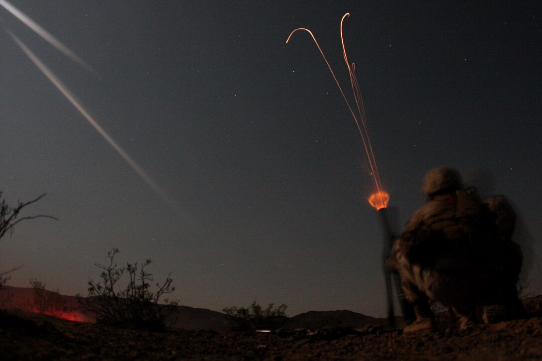 Lance Cpl. Tessillo Nunez and Pfc. Eric Flaherty, a mortar team with Company E, 2nd Battalion, 7th Marine Regiment, launch a 60 mm lightweight mortar into the site where their squad set up an ambush Tuesday night in the Combat Center's Rainbow Ridge Training Area. The company inserted into the training area on CH-53 Super Stallion helicopters and set up patrol bases where they launched security and reconnaissance patrols which culminated in live-fire night ambushes.