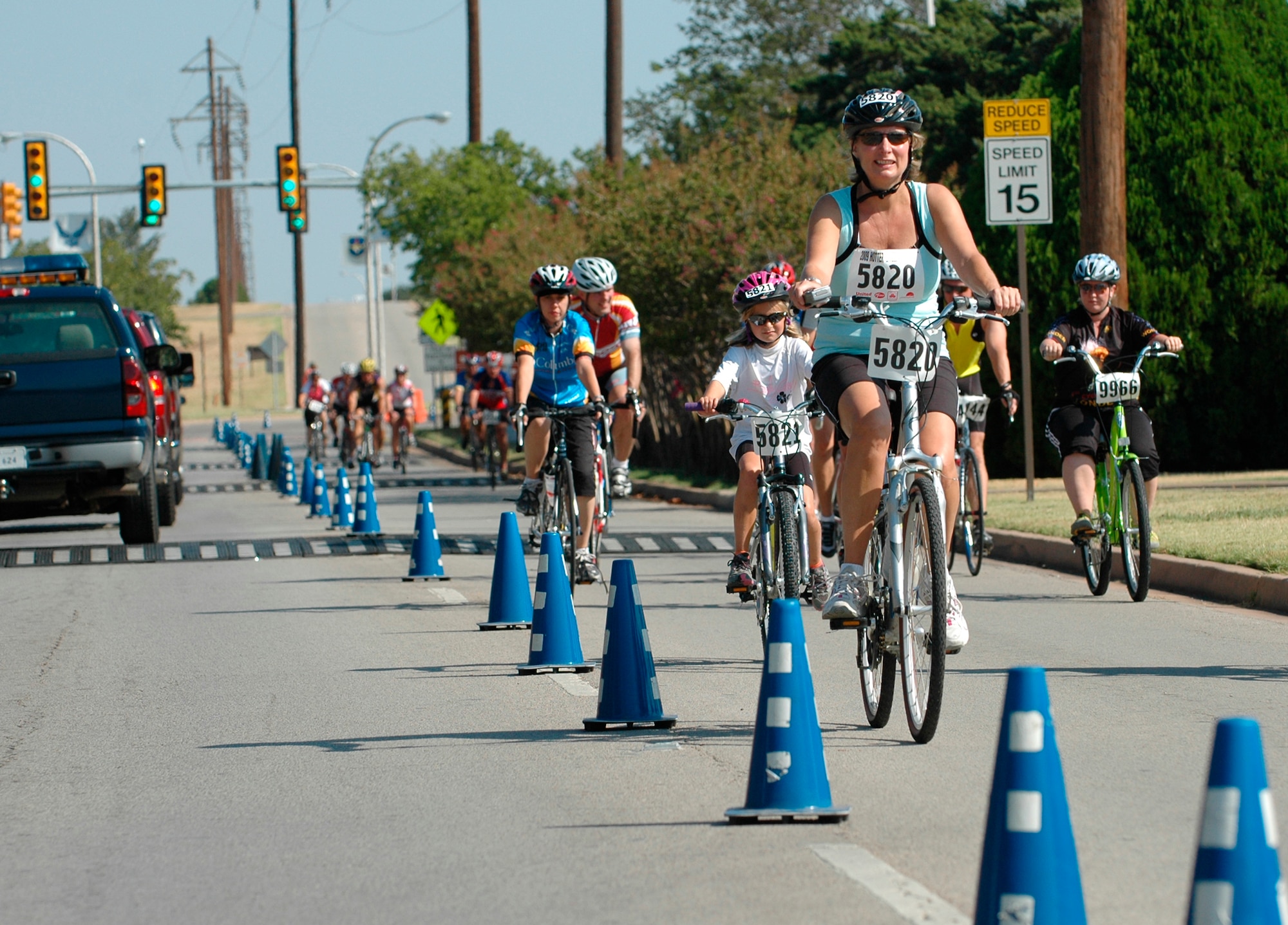 Cyclists pass through Sheppard's Main Gate during the Hotter N’ Hell bike race, the largest one-day international bicycle race Aug. 29. About 14,200 athletes participated in the race, breaking the records for the number of participants in the race and the number of volunteers from Sheppard. About 2,000 Sheppard members volunteered to provide rest stops, medical assistance, set-up and teardown support to make the race possible. (U.S. Air Force photo/Harry Tonemah) 
