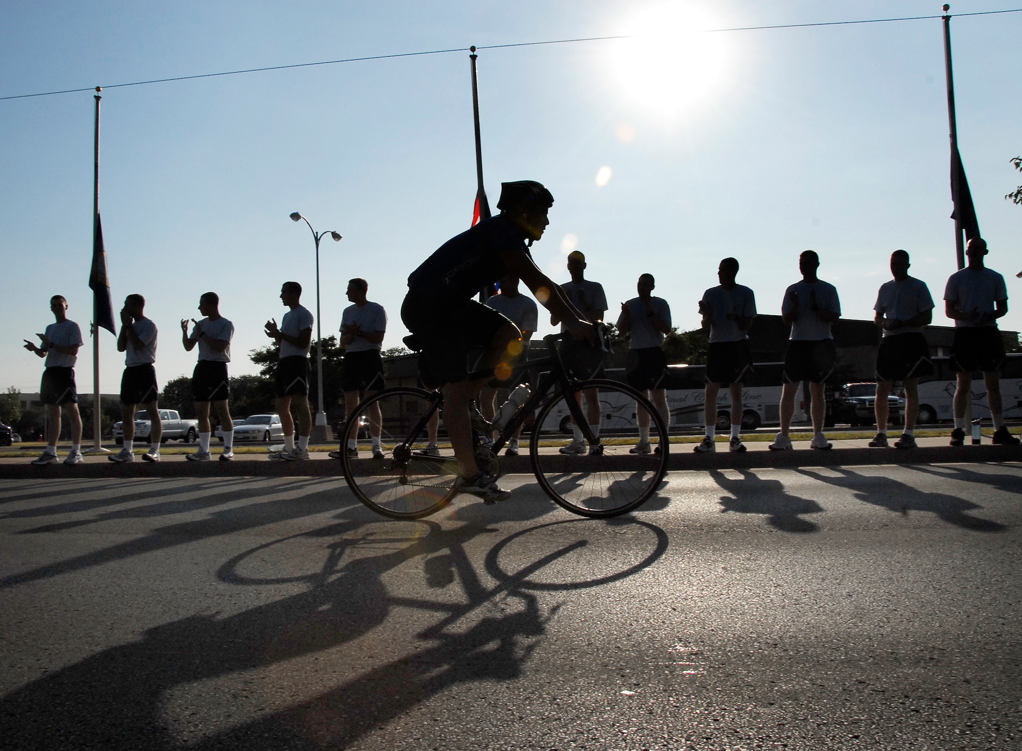 Airmen cheer on a cyclist passing through Sheppard during the Hotter N’ Hell bike race, the largest one-day international bicycle race Aug. 29. About 14,200 athletes participated in the race, breaking the records for the number of participants in the race and the number of volunteers from Sheppard. About 2,000 Sheppard members volunteered to provide rest stops, medical assistance, set-up and teardown support to make the race possible. (U.S. Air Force photo/Harry Tonemah) 

