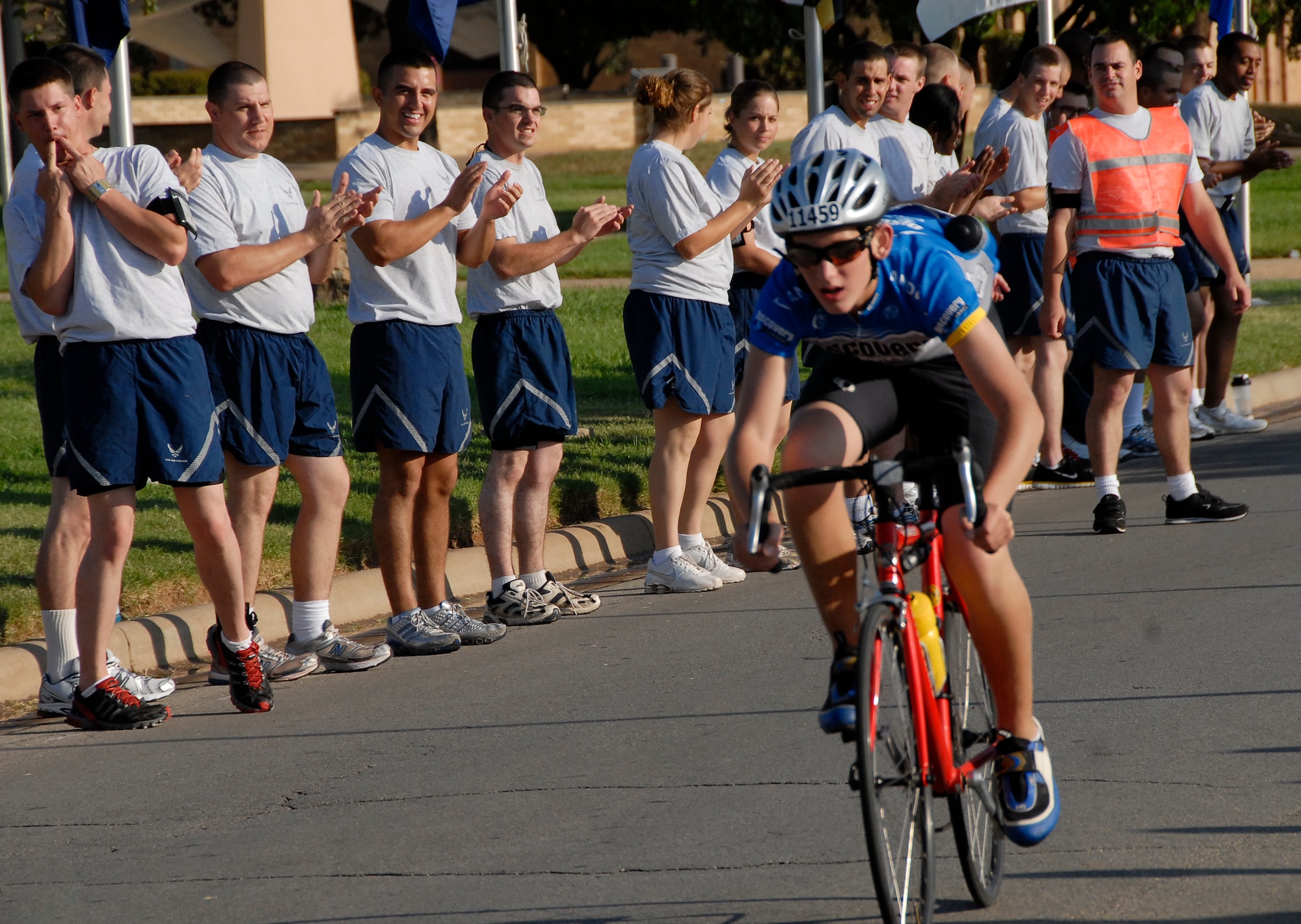Airmen cheer on a cyclist passing through Sheppard during the Hotter N’ Hell bike race, the largest one-day international bicycle race Aug. 29. About 14,200 athletes participated in the race, breaking the records for the number of participants in the race and the number of volunteers from Sheppard. About 2,000 Sheppard members volunteered to provide rest stops, medical assistance, set-up and teardown support to make the race possible. (U.S. Air Force photo/Harry Tonemah) 

