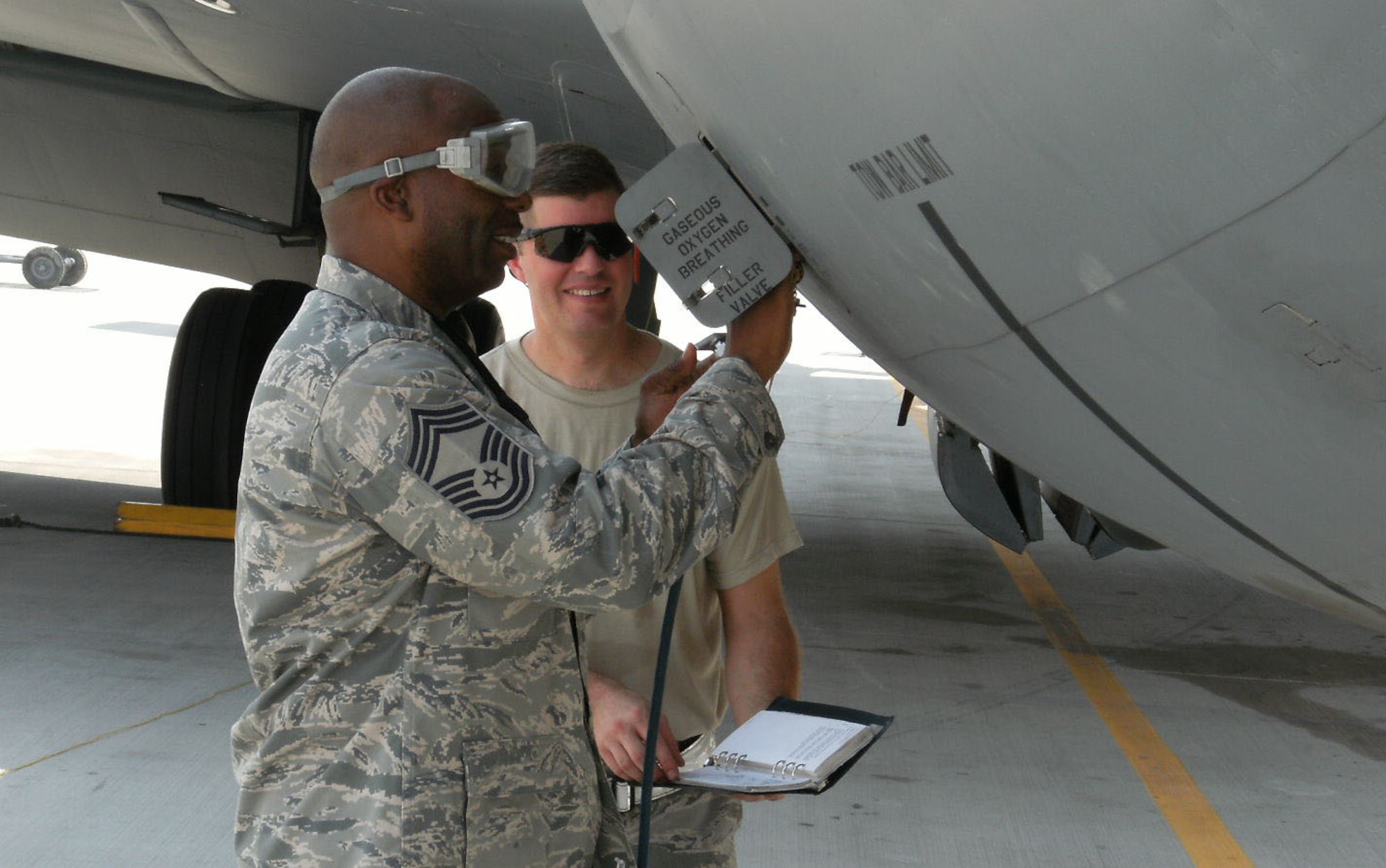 Chief Master Sgt. Antonio Kitt, 340th Expeditionary Aircraft Maintenance Unit, and Tech. Sgt. Robert Shou, 340th EAMU, service the oxygen system on a KC-135 Stratotanker at a deployed location in Southwest Asia, Aug. 8. Chief Kitt is deployed from McConnell Air Force Base, Kan. Sergeant Shou is deployed from MacDill AFB, Fla. (courtesy photo)